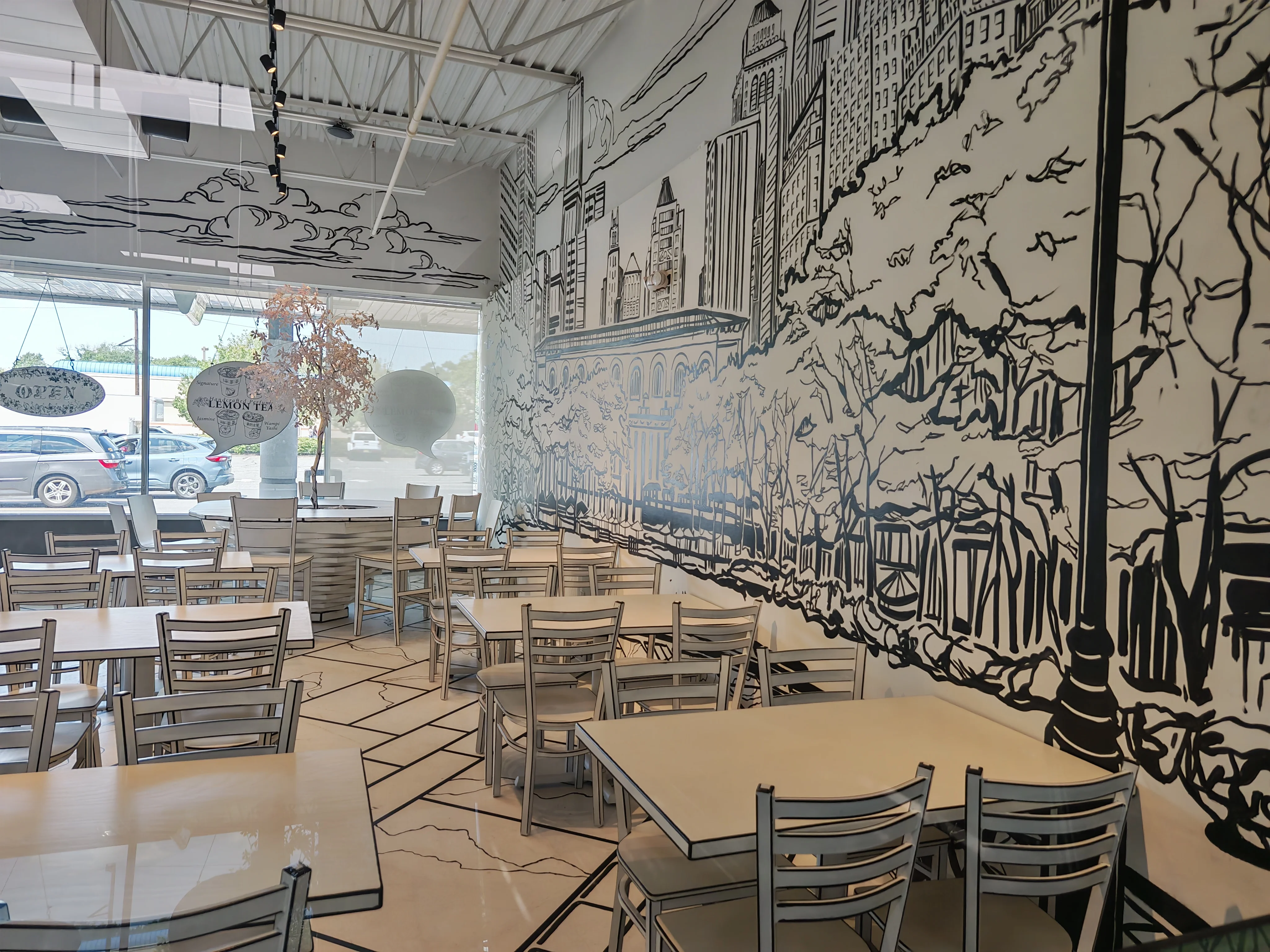 An immersive, black and white wall mural at Chopsticks Charm that creates an illusion of a path leading into a tunnel of trees, complete with a 2-D style bench.