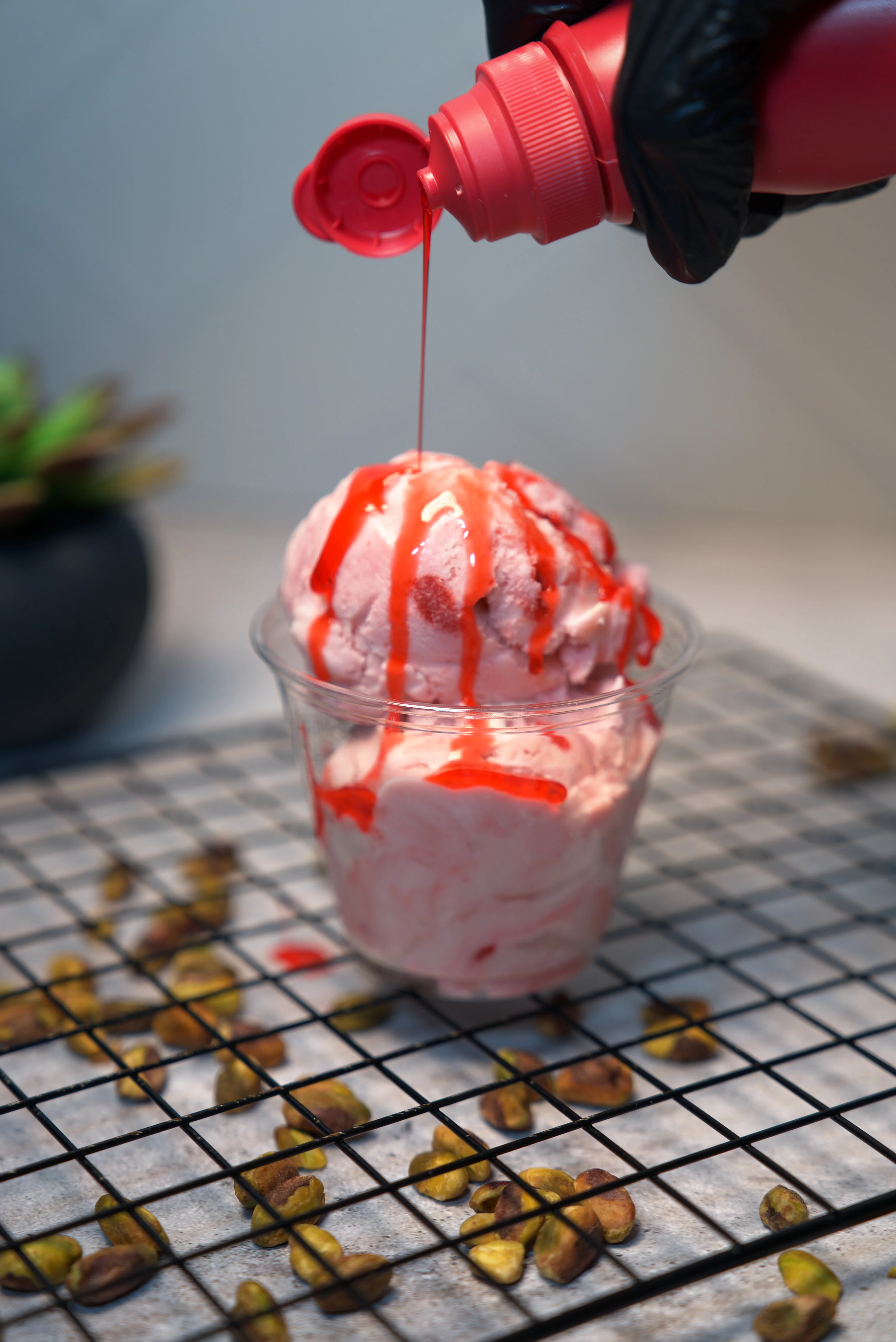 A round dessert topped with a scoop of ice cream and crushed pistachios, presented on a white plate.