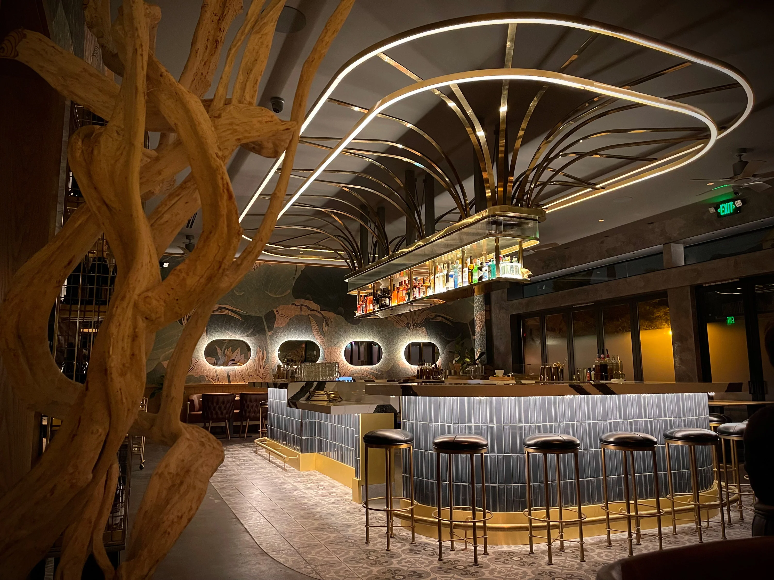 Kingfisher Bar with gold barstools and liquor display at night.