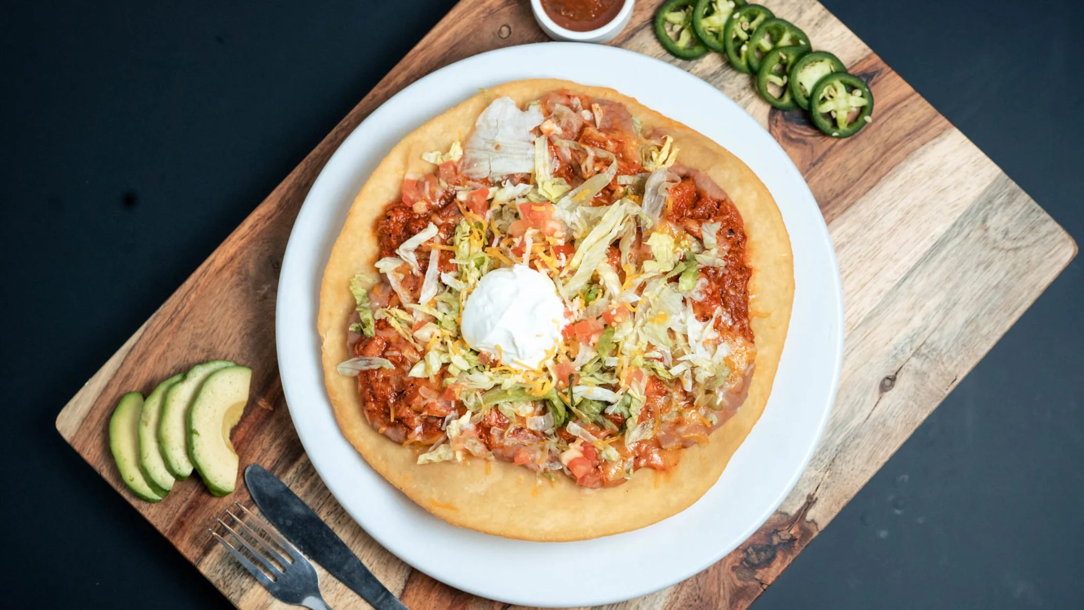 Delicious Mexican tostada topped with fresh vegetables and sour cream