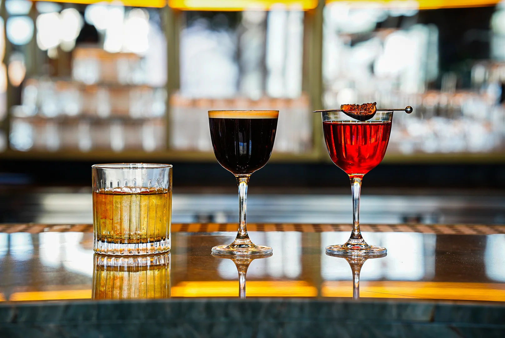 Three stylish cocktails on a bar counter