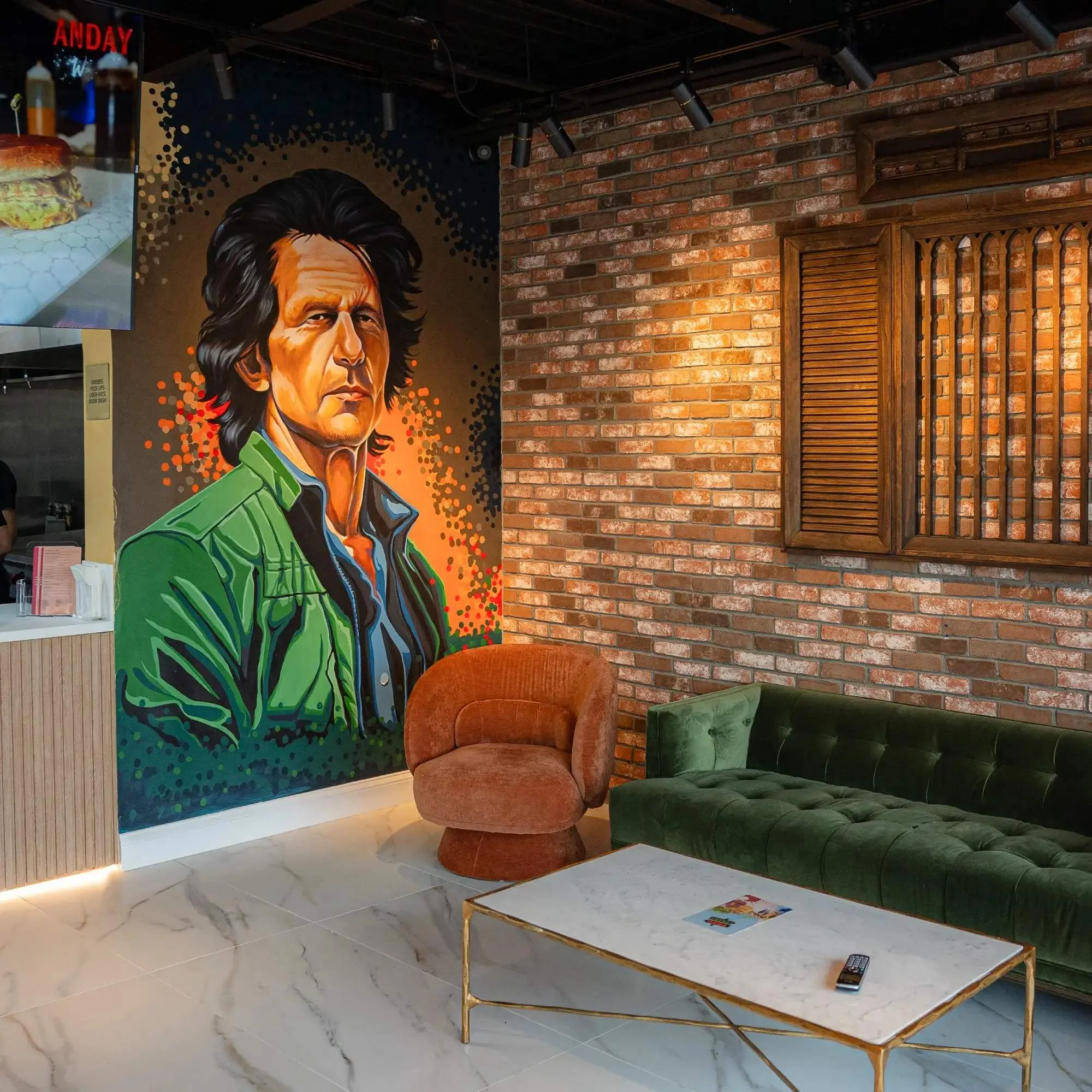 Comfortable chairs against a brick wall with large portrait mural on wall.