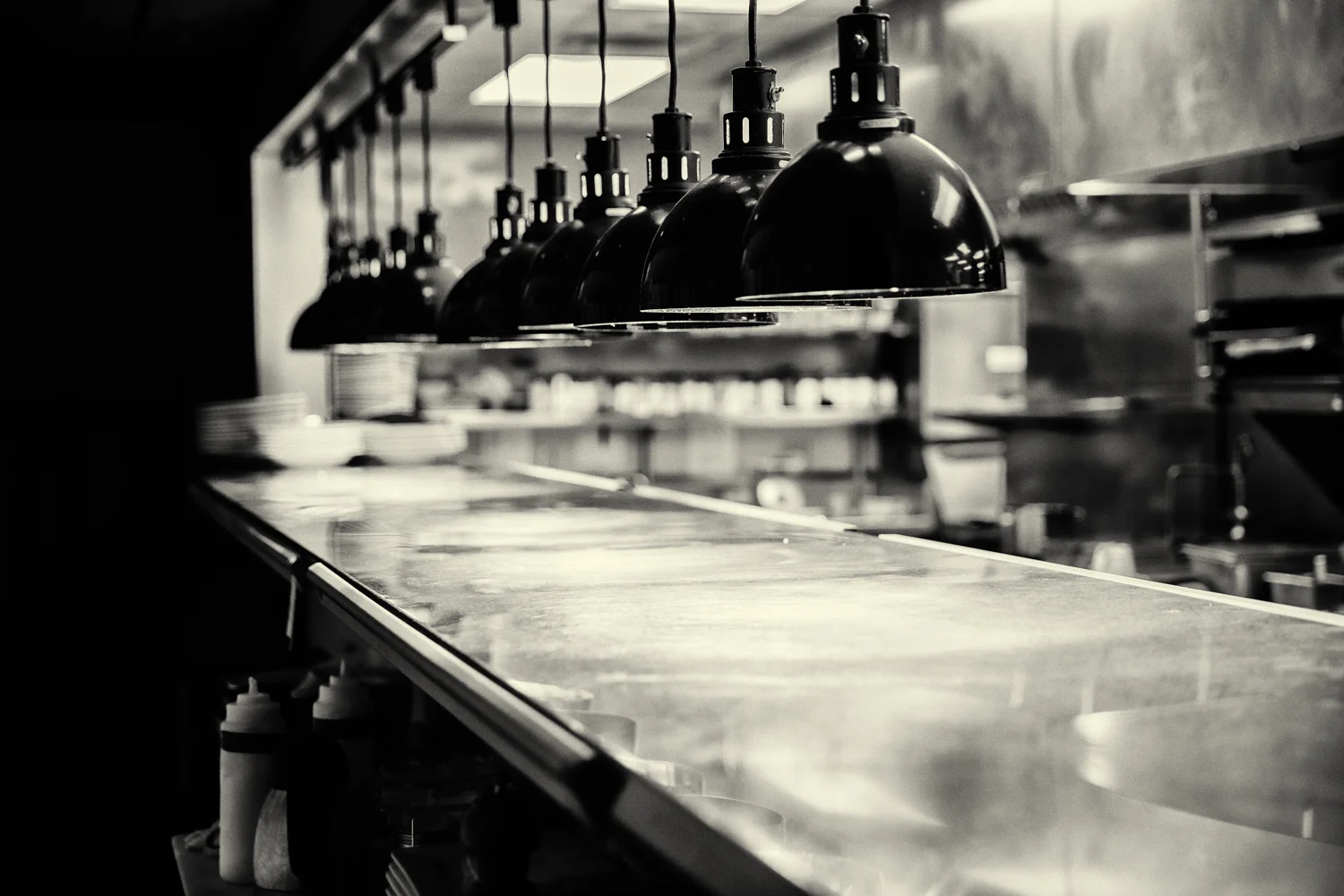 Restaurant kitchen with hanging lights and stainless steel surfaces