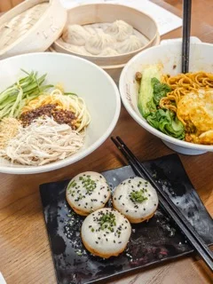 A plate of dumplings and noodles served with garnishes.