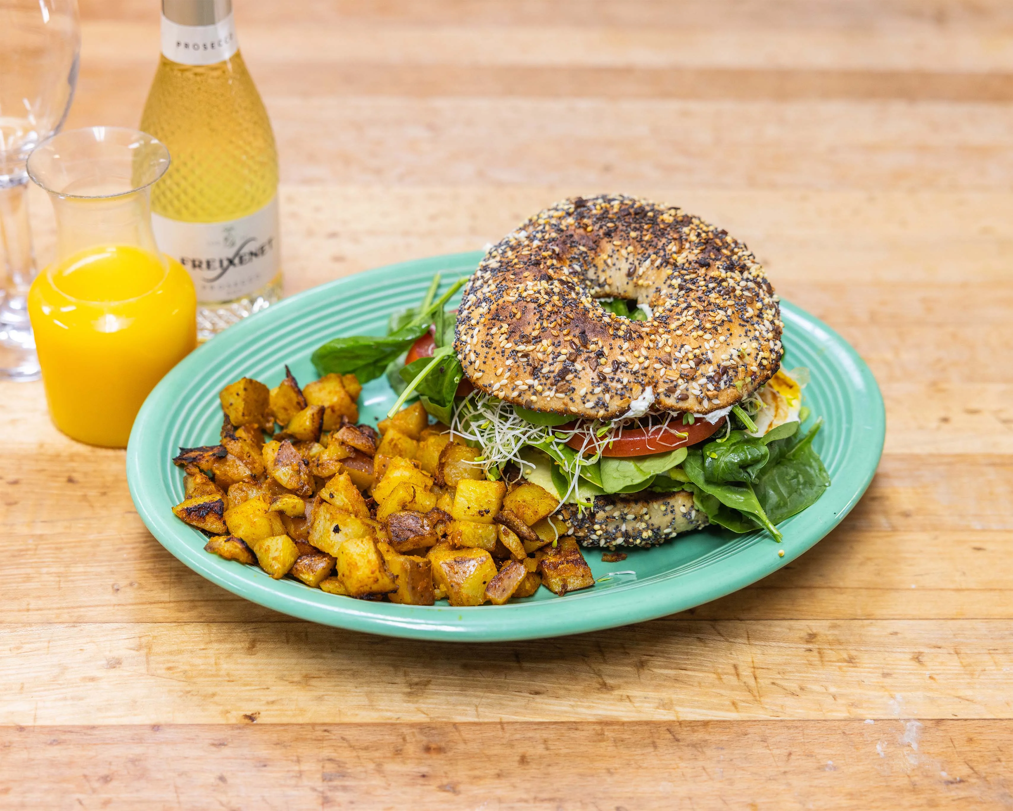 Everything bagel breakfast sandwich with roasted potatoes and orange juice