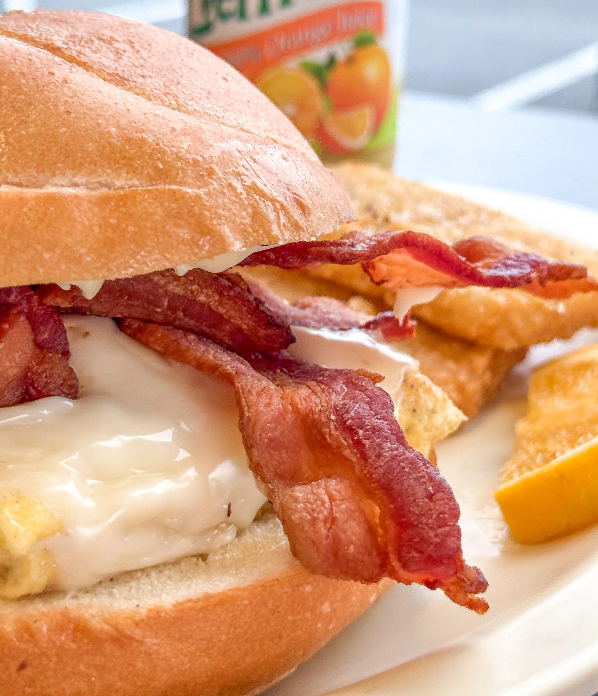 Thick-cut bacon and melted cheese stacked over eggs on a toasted roll with crispy hash browns