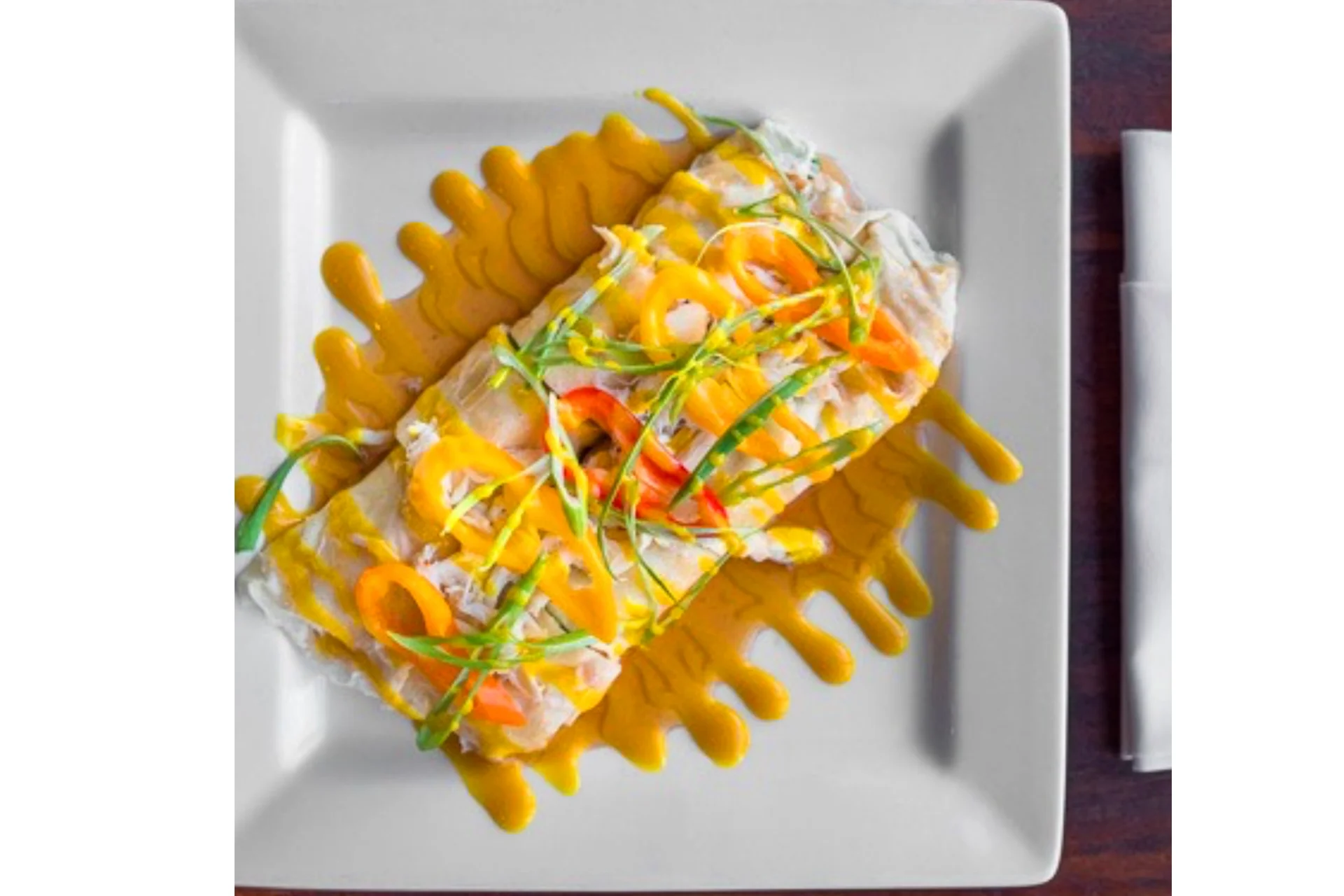 Colorful Mexican enchiladas drizzled with sauce and garnished with vegetables