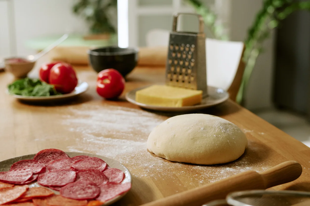 Preparing pizza dough with fresh ingredients on a wooden table