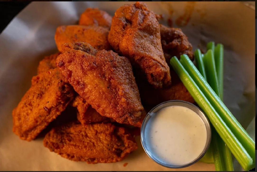 Crispy fried chicken wings served with celery sticks and a small bowl of ranch dressing.