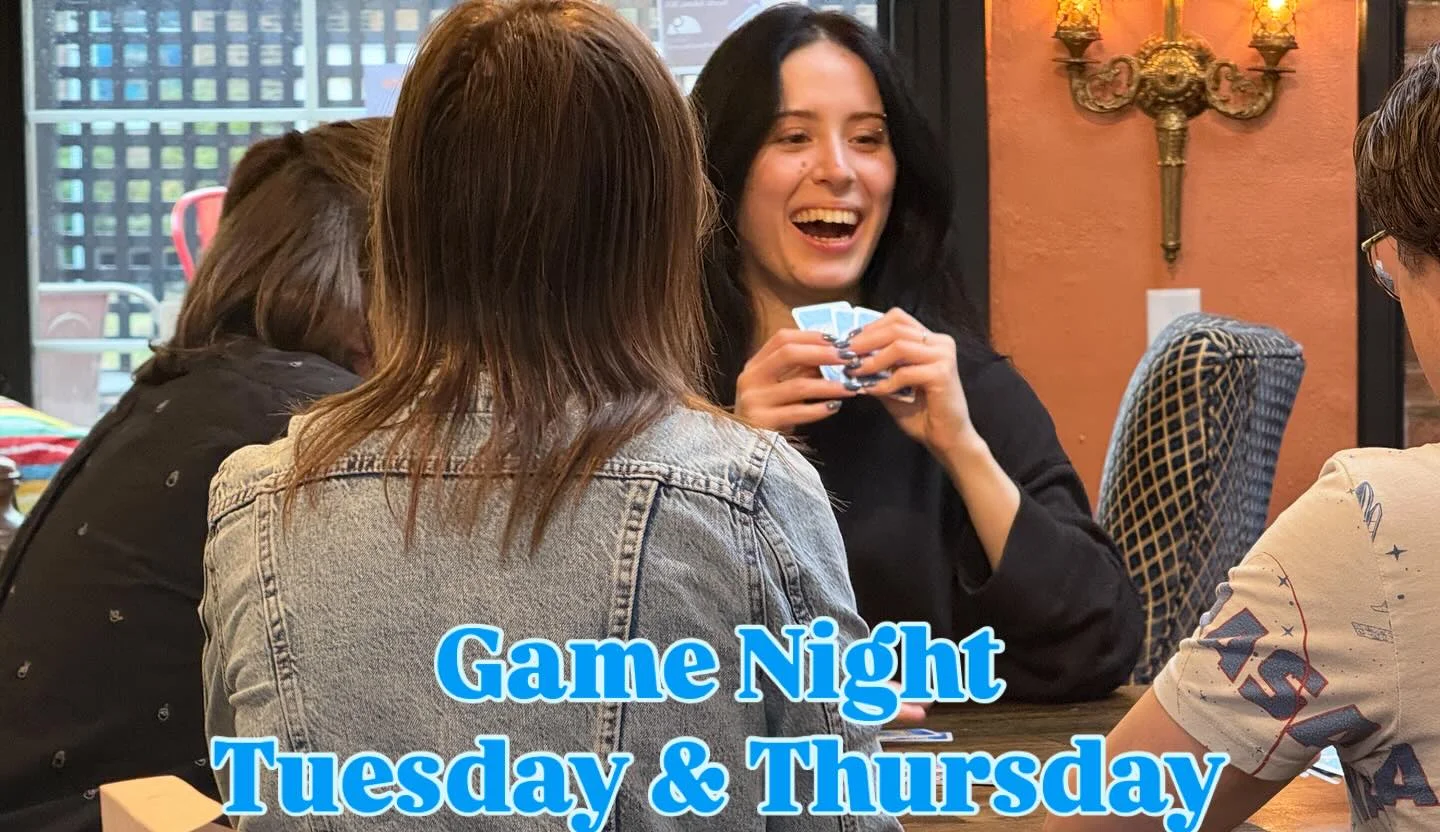 A group of friends enjoying a game night at a table while playing card games. Laughter and excitement fill the atmosphere, with various board games visible in the foreground.