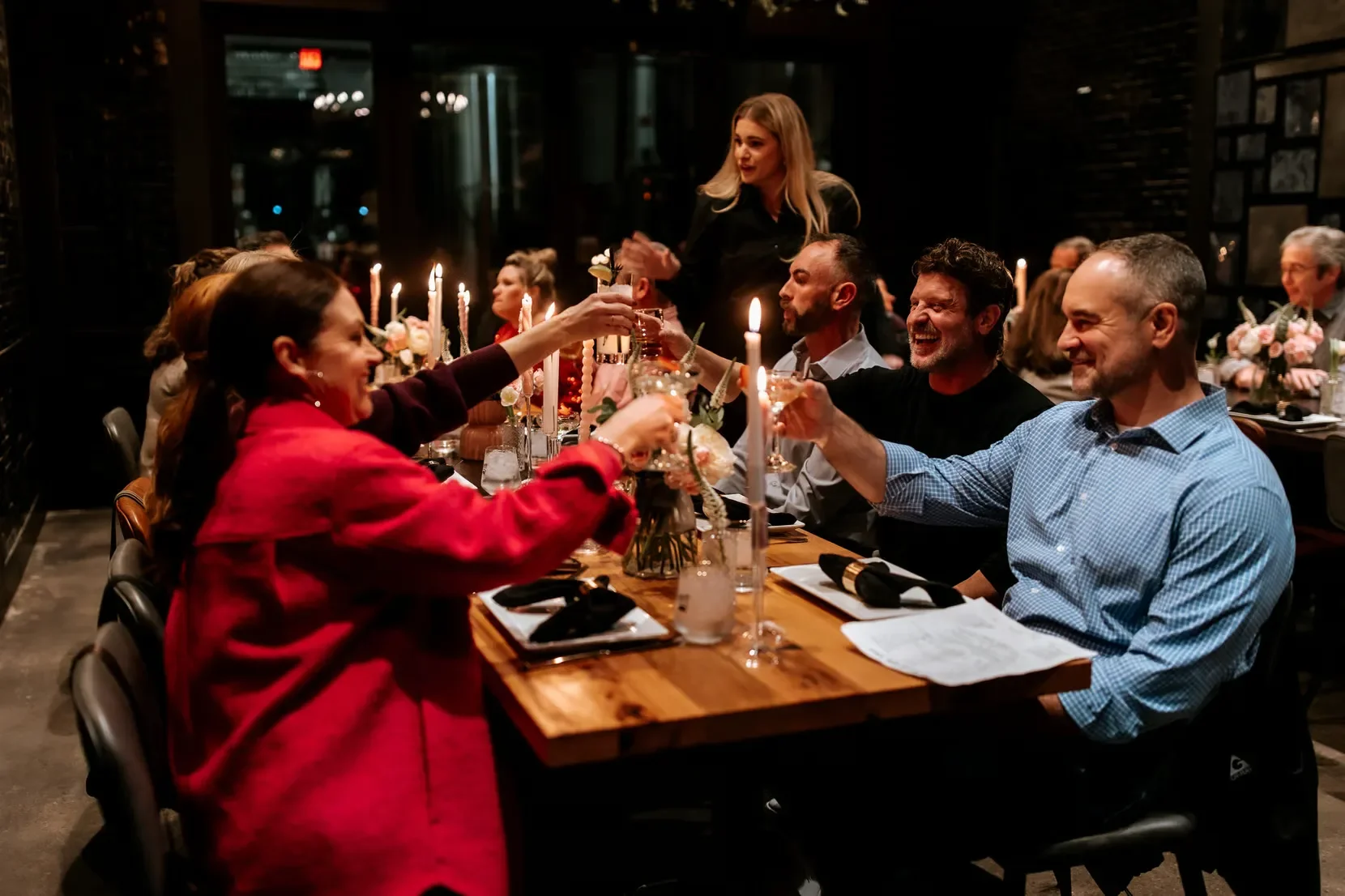 Elegant dining scene with guests toasting at a candlelit table