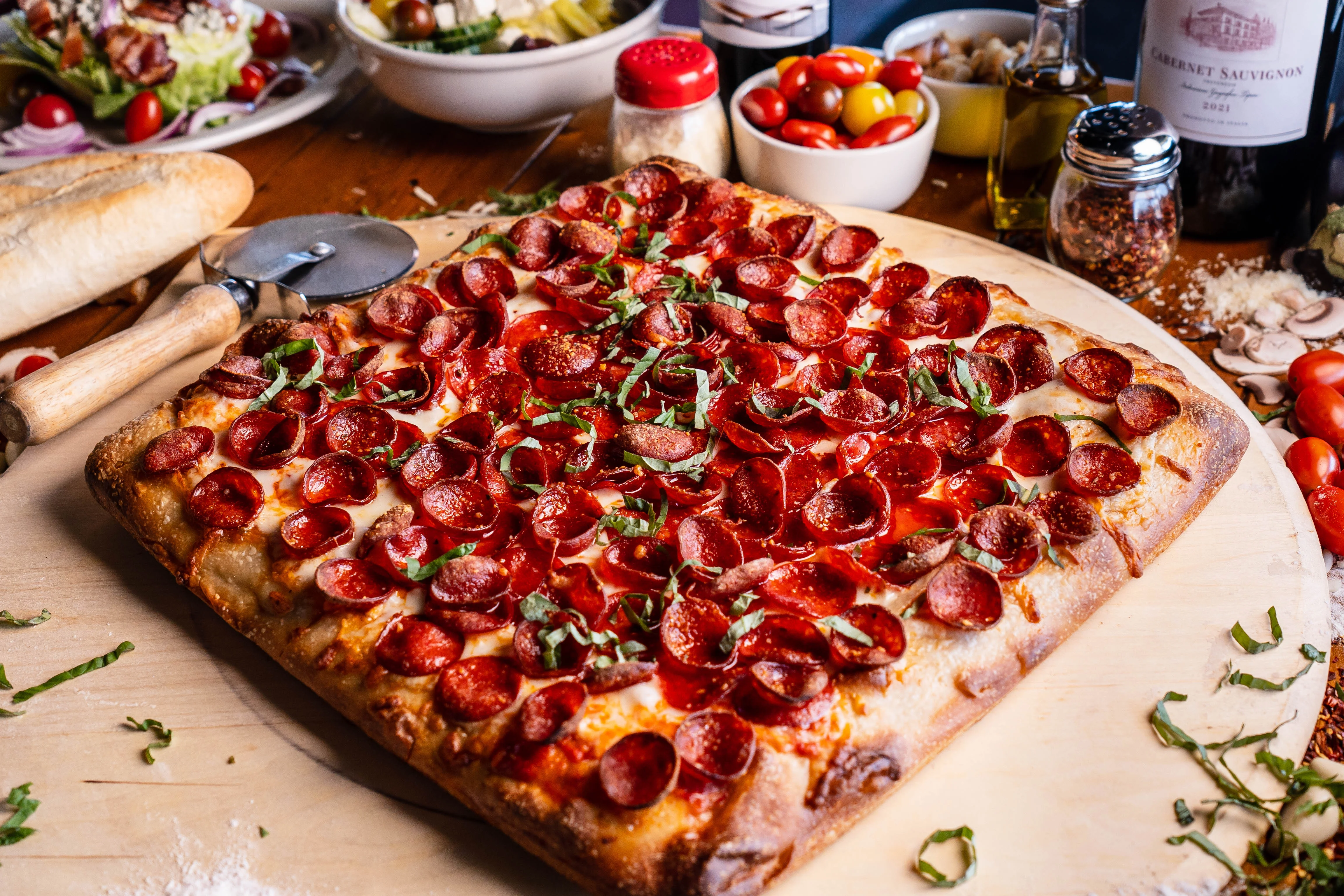 Pepperoni pizza with fresh basil on a wooden board