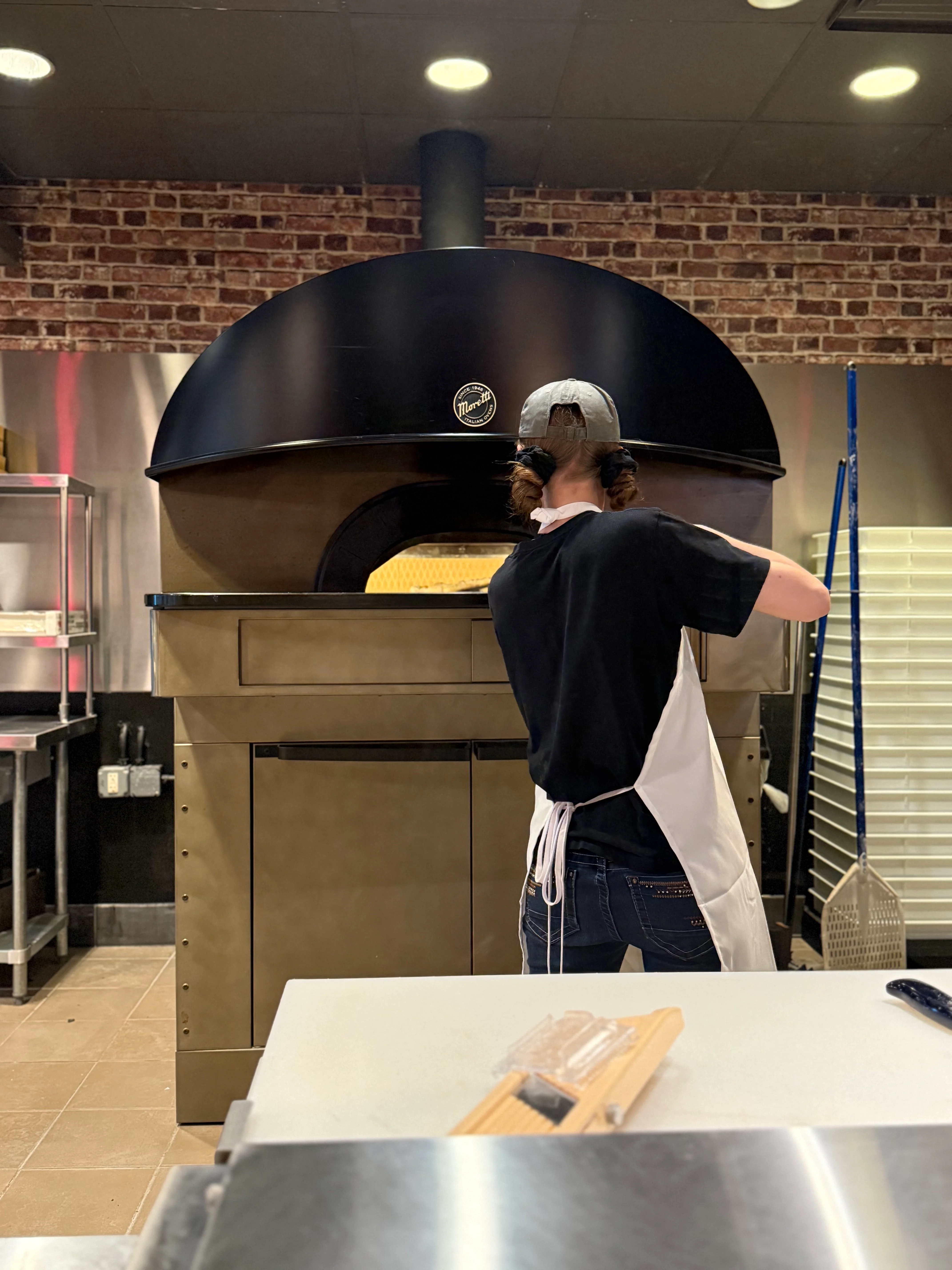 Chef preparing pizza in a wood-fired oven