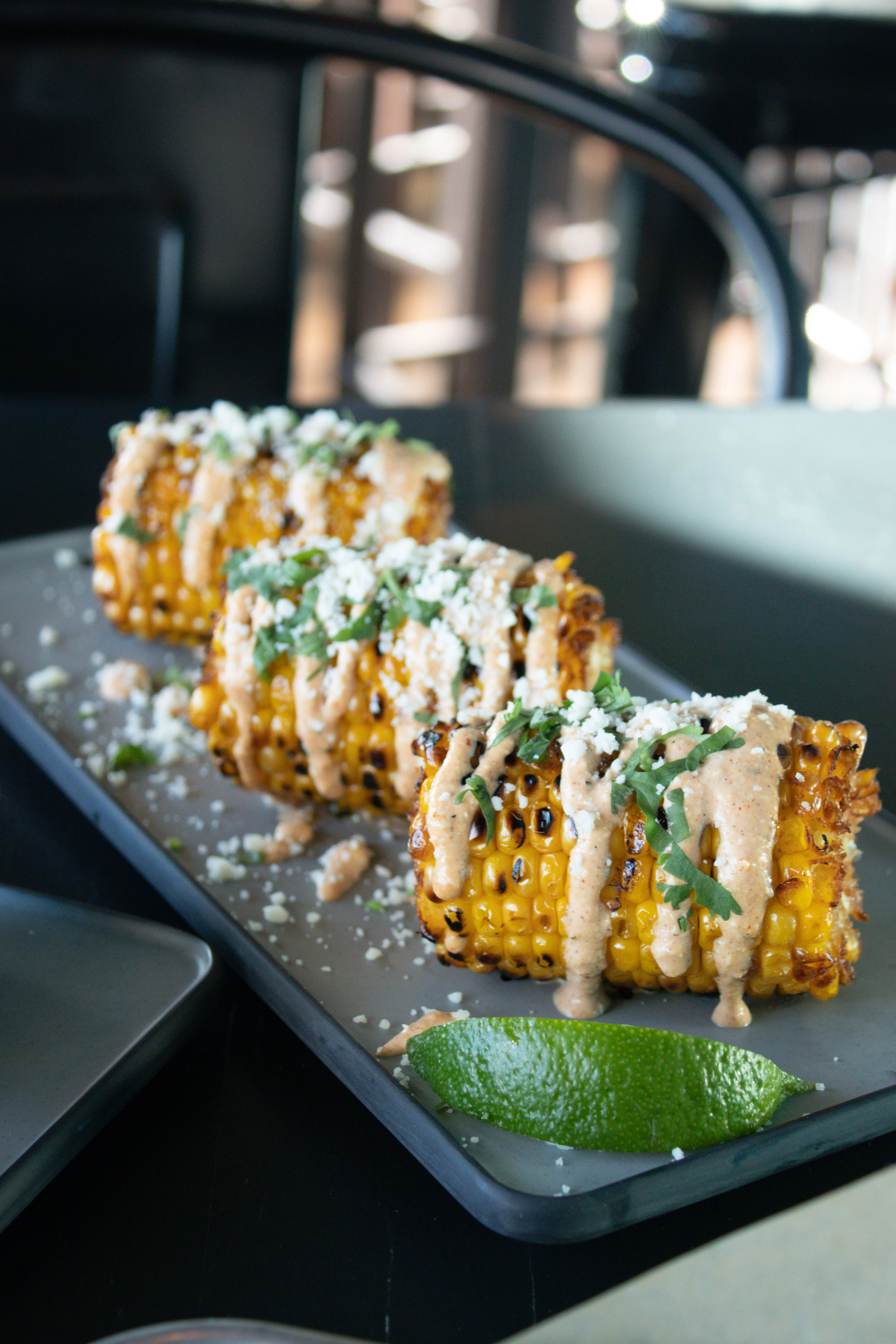 Grilled Mexican elote topped with cheese and sauce