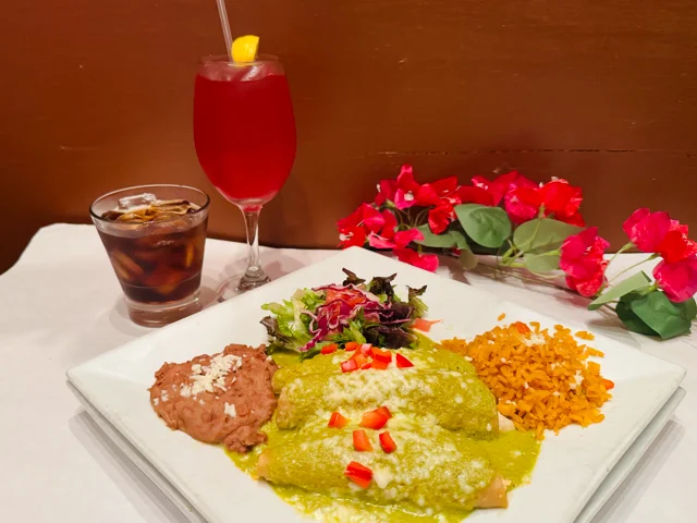 Plate of enchiladas verdes with sides in a vibrant restaurant setting