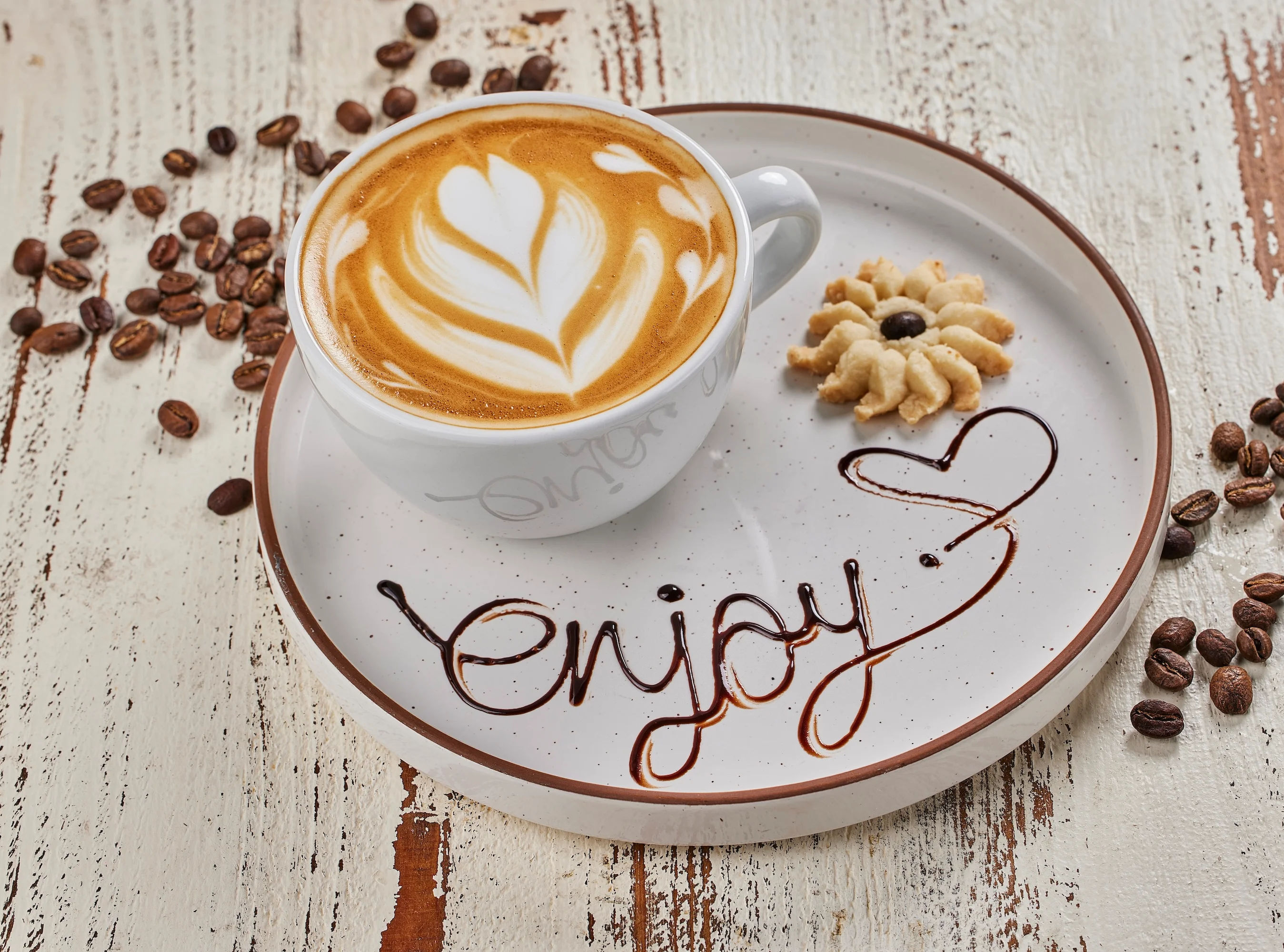 Artisan latte with heart design and cookie on a rustic plate