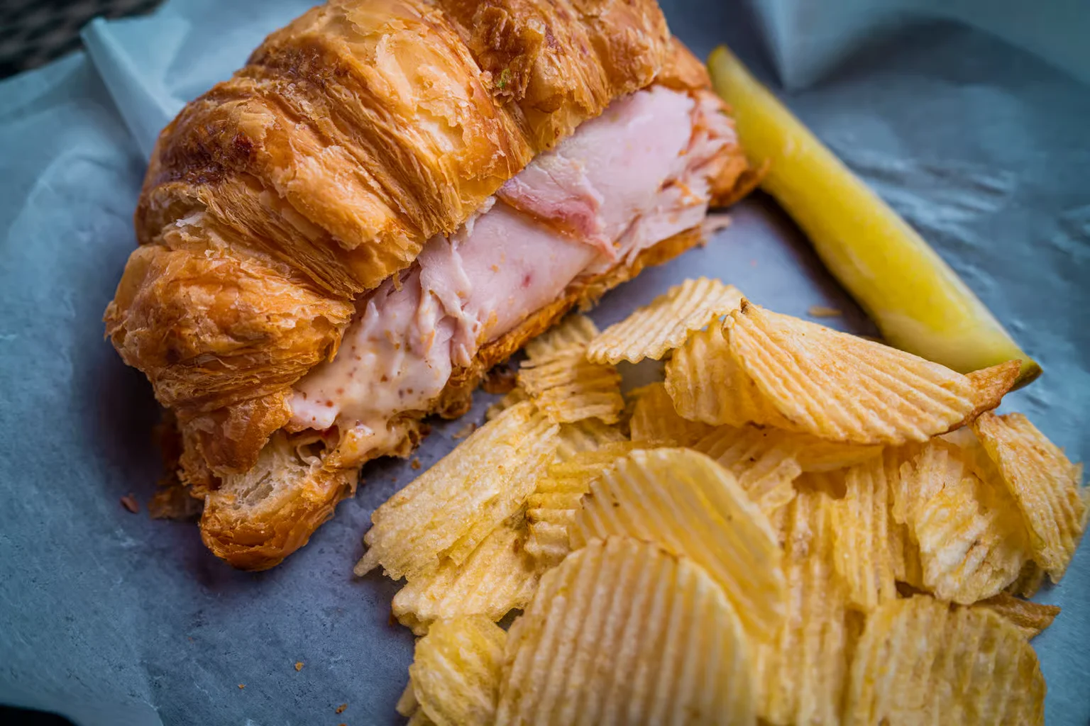 A croissant sandwich and chips