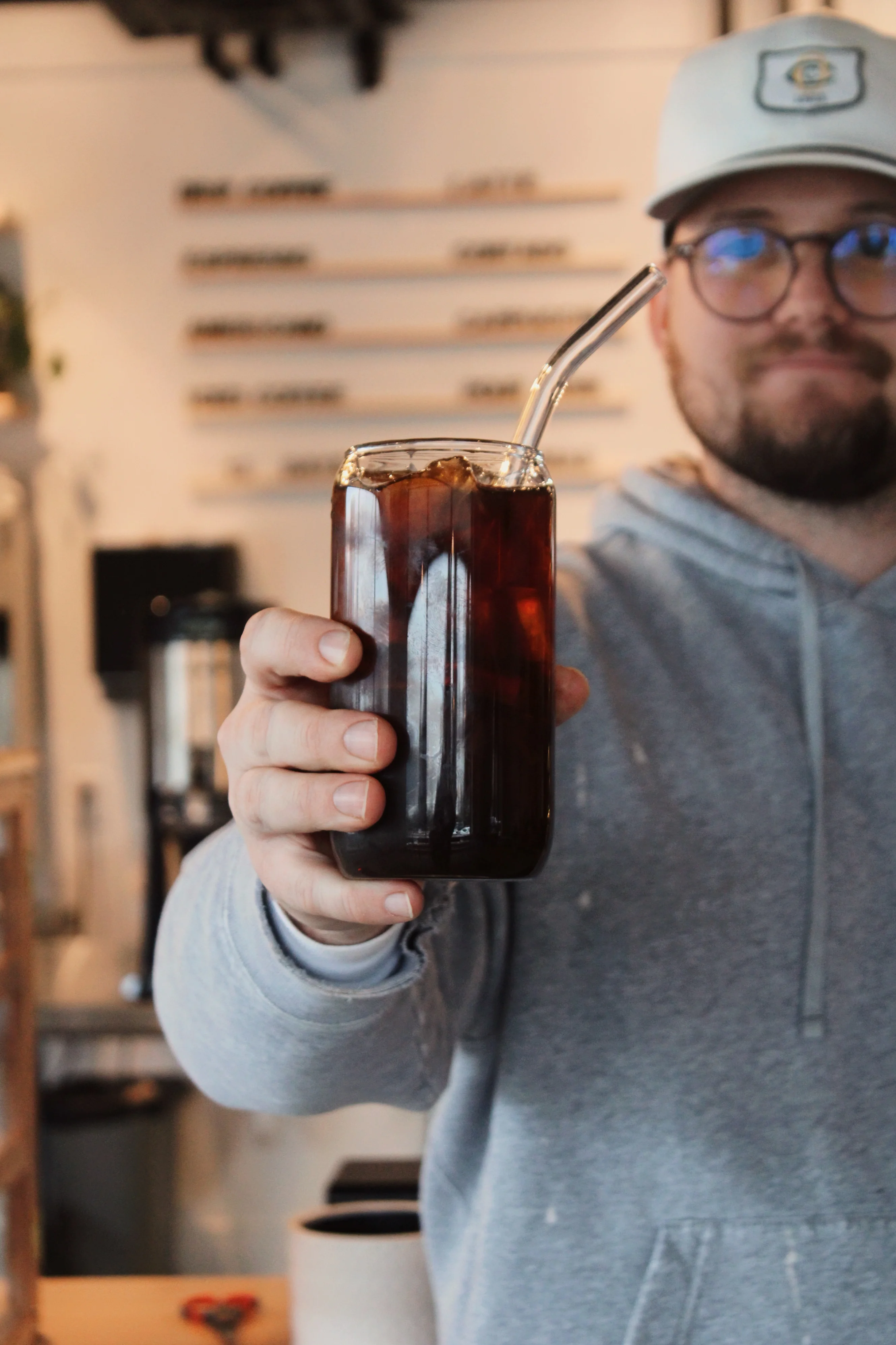 Barista holding a glass of cold brew coffee with a straw
