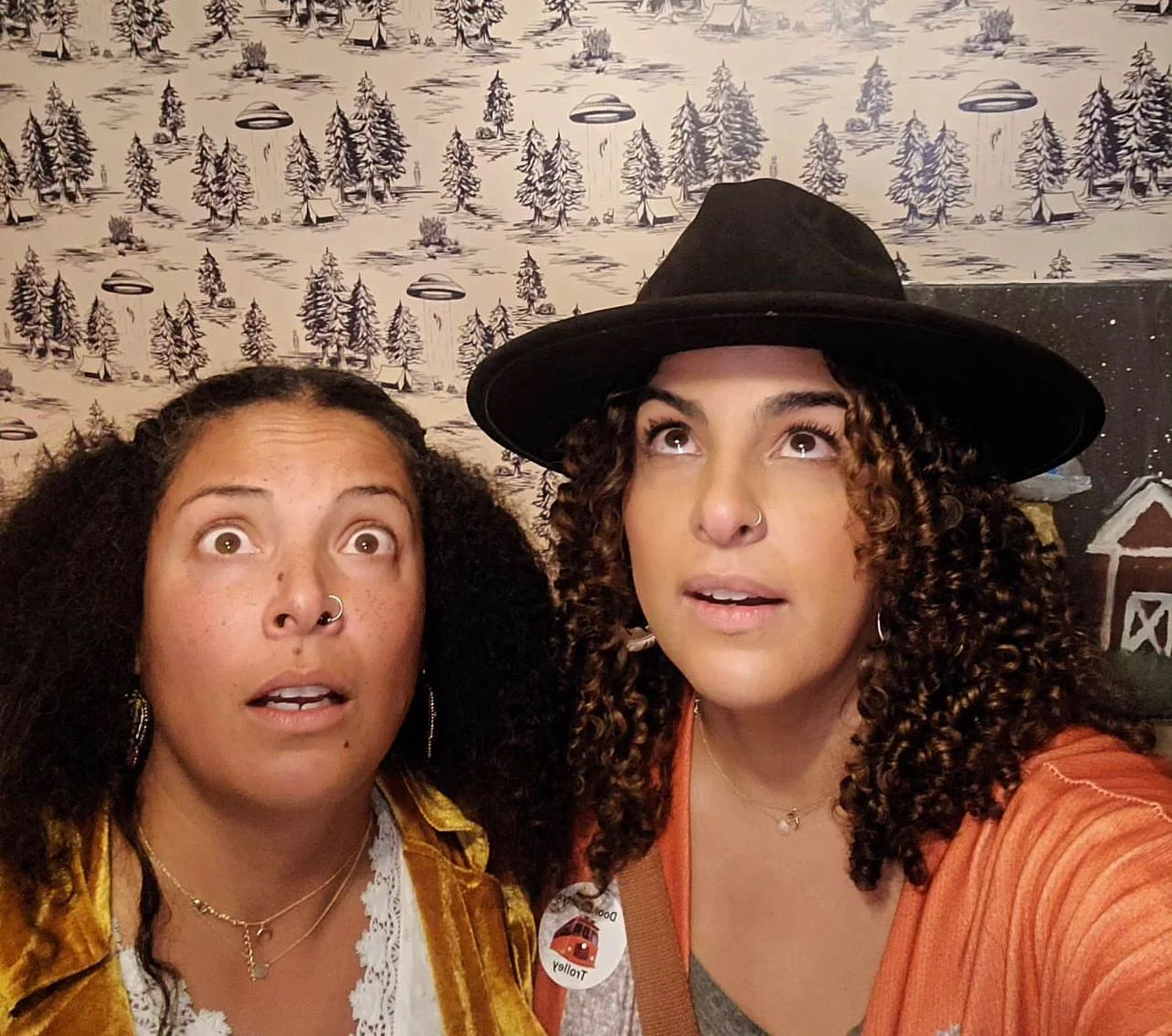 Two women looking surprised in a quirky, themed setting