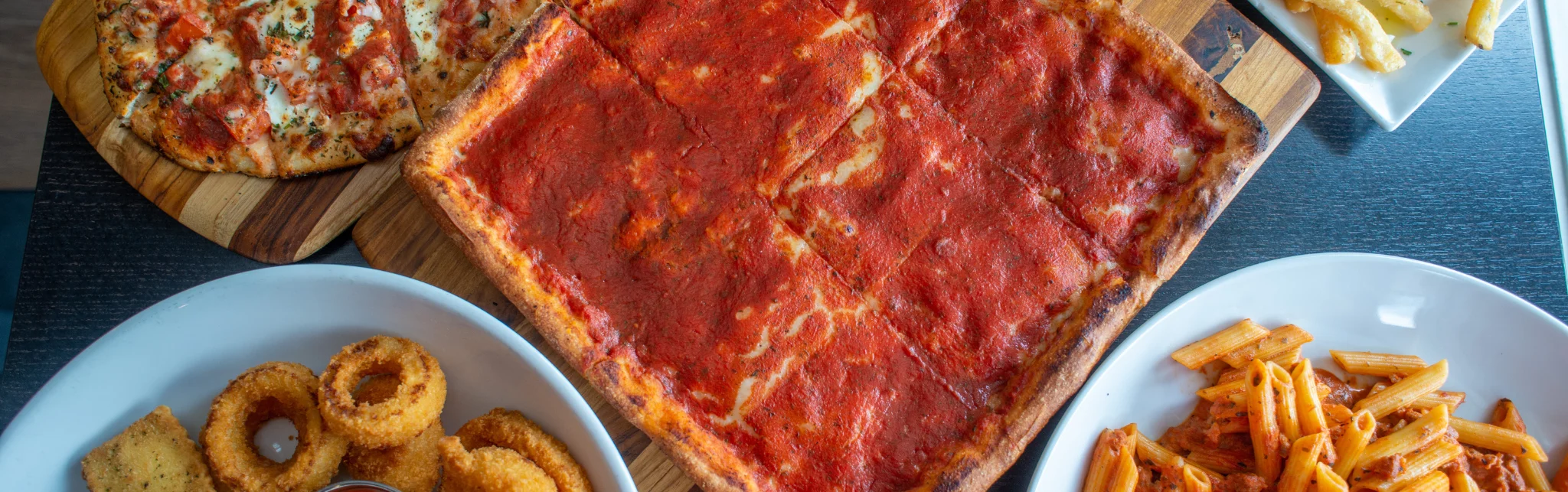 Italian pizza and pasta spread on a wooden table