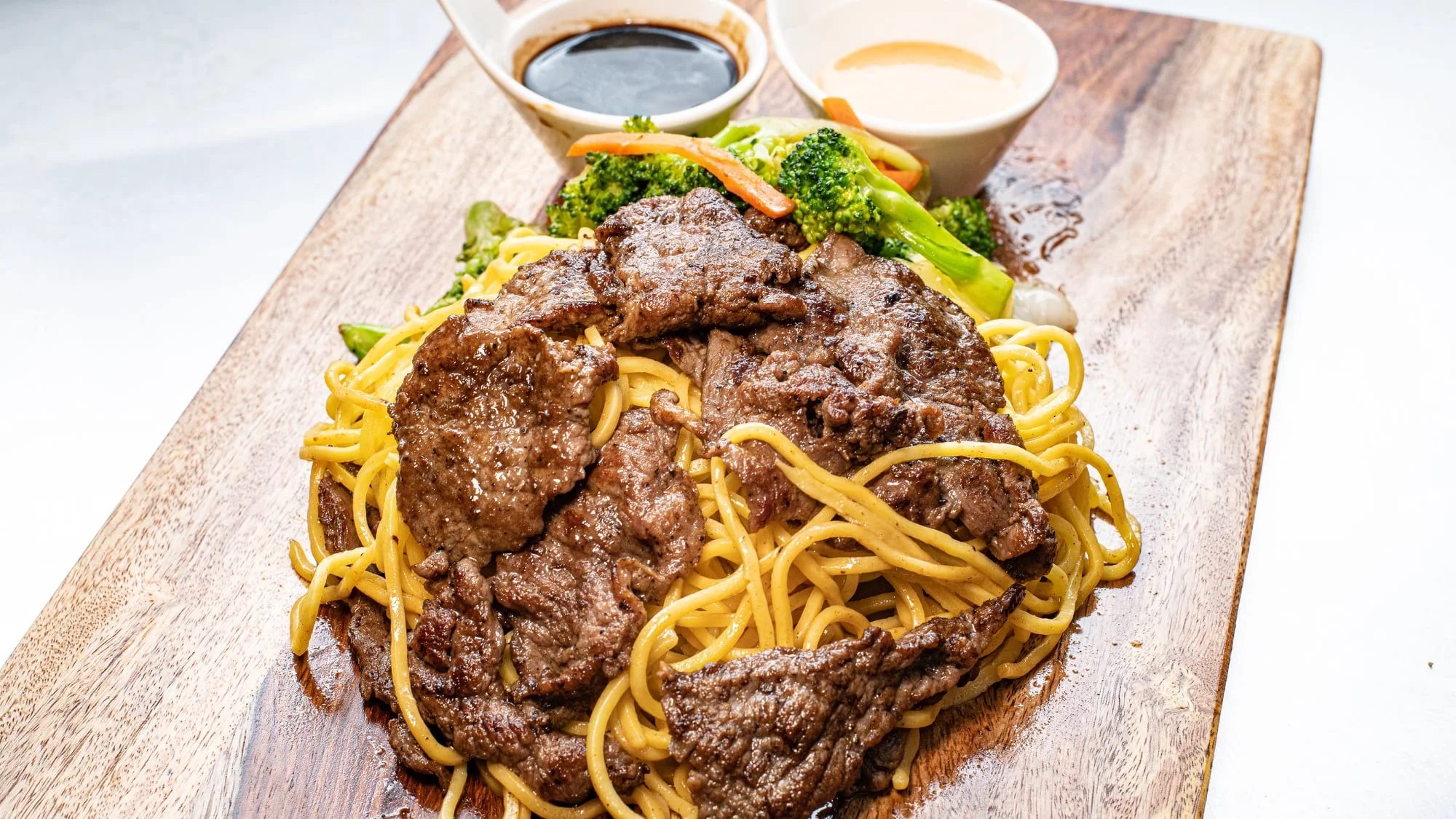 Beef chow mein served with vegetables and dipping sauces