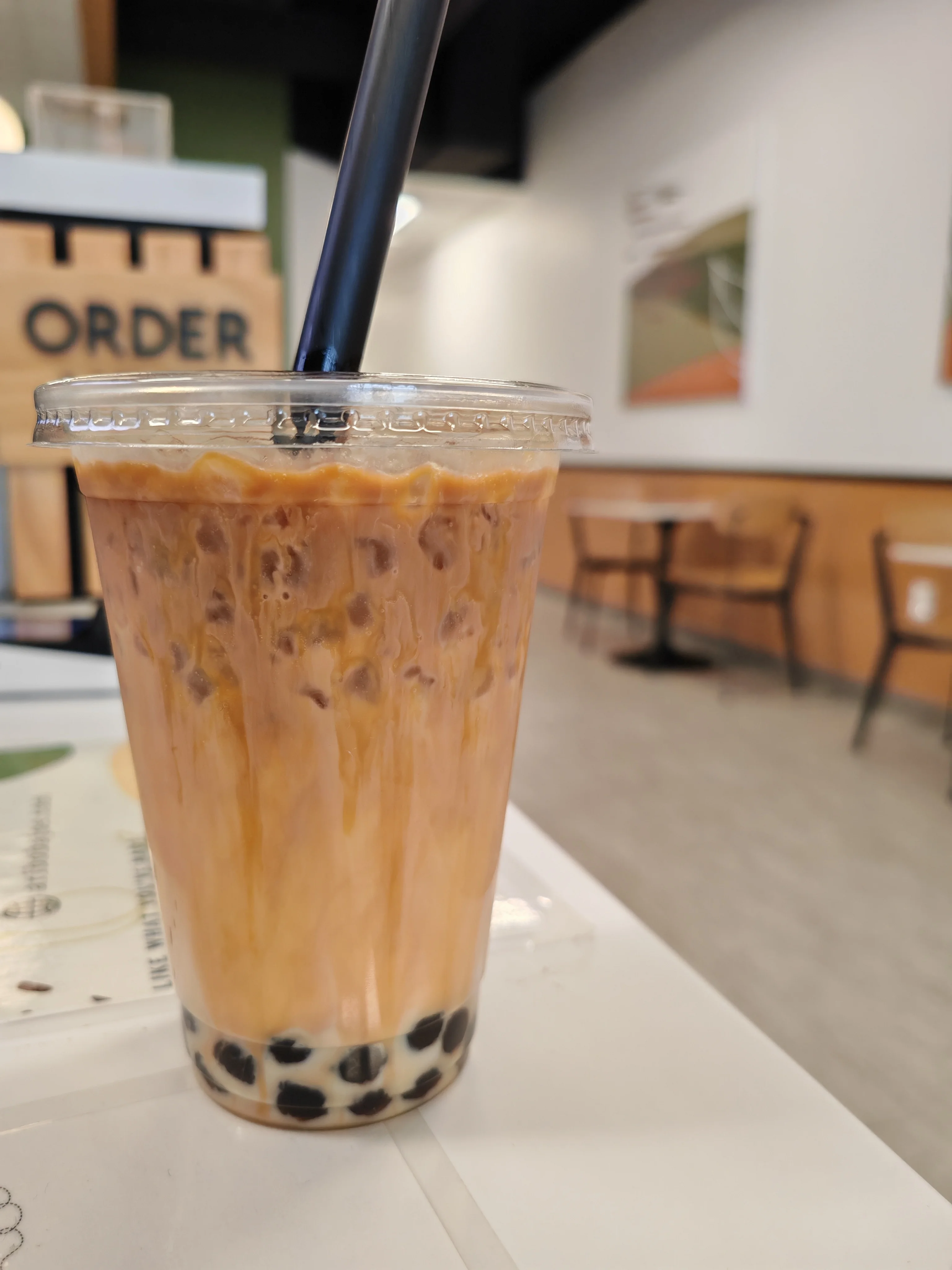An iced drink with a logo featuring a red panda, topped with whipped cream and chocolate drizzle.