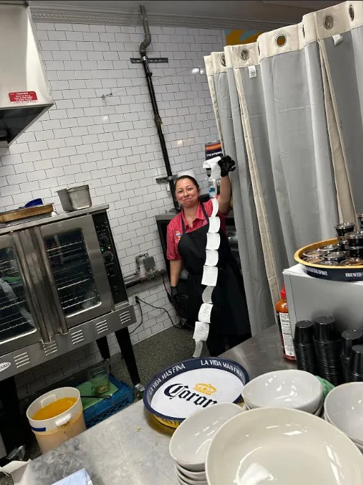 Restaurant staff holding a long ticket roll in a busy kitchen
