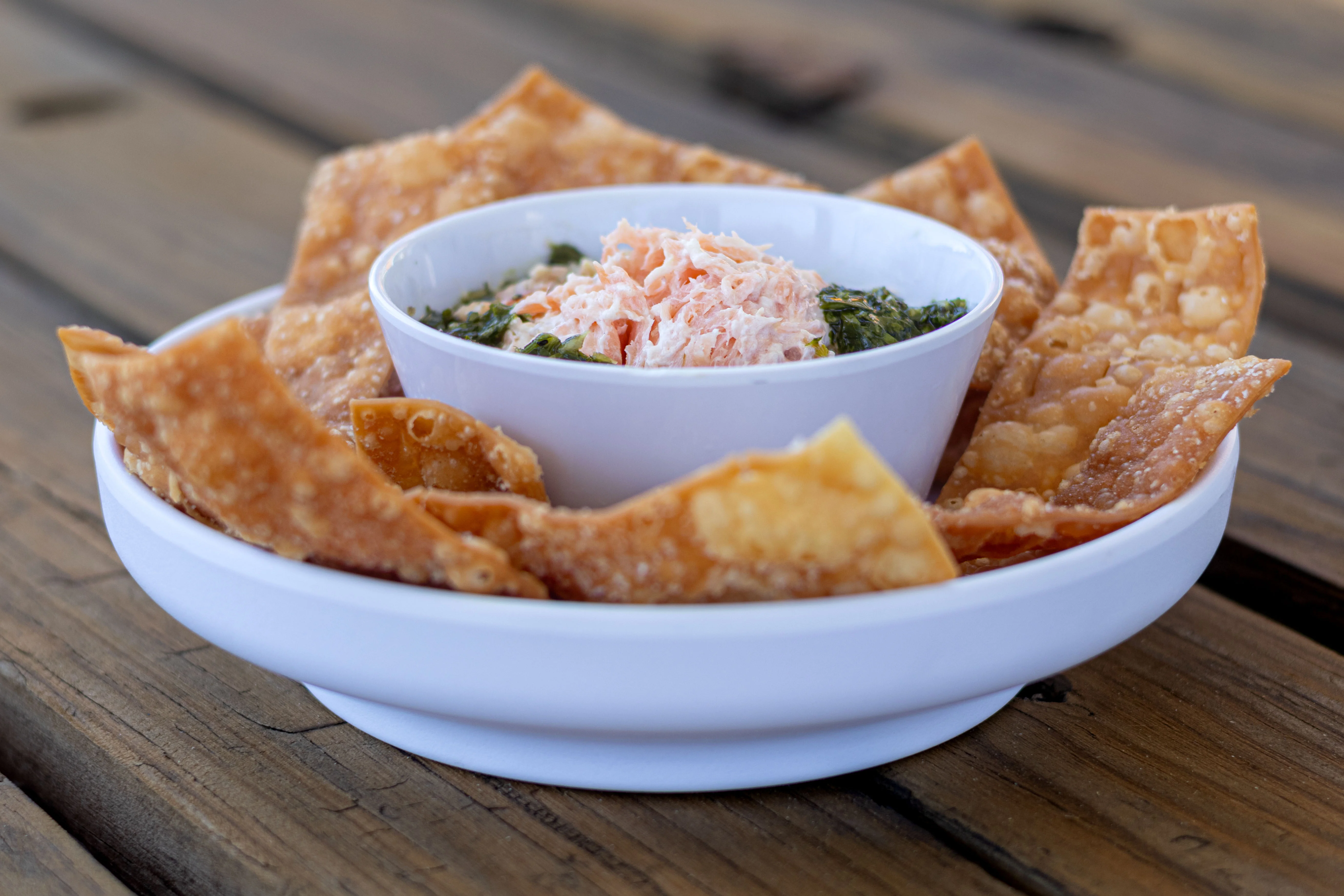 Crispy chips served with a creamy dip and shredded topping in a bowl.