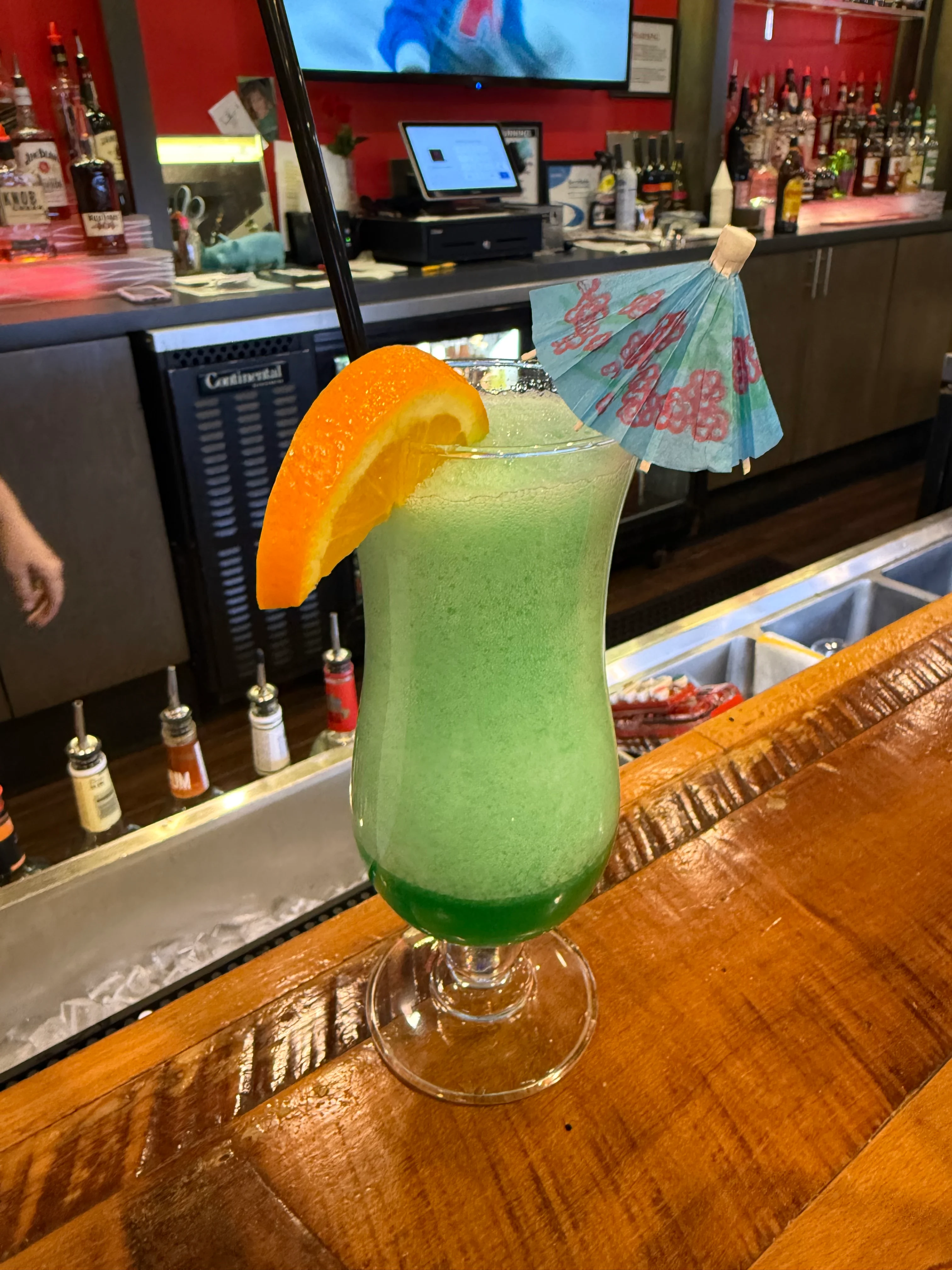 Colorful tropical cocktail with an umbrella and orange slice