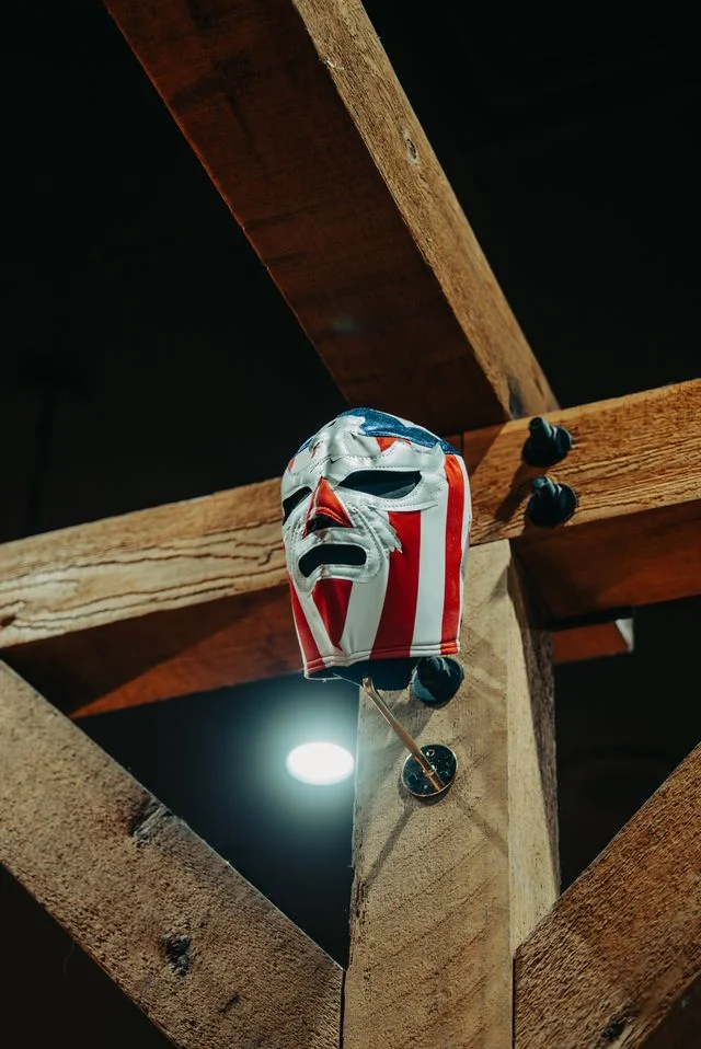 Colorful luchador mask hanging on wooden beam