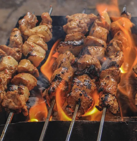 Grilled kebabs over open flames in a traditional setting