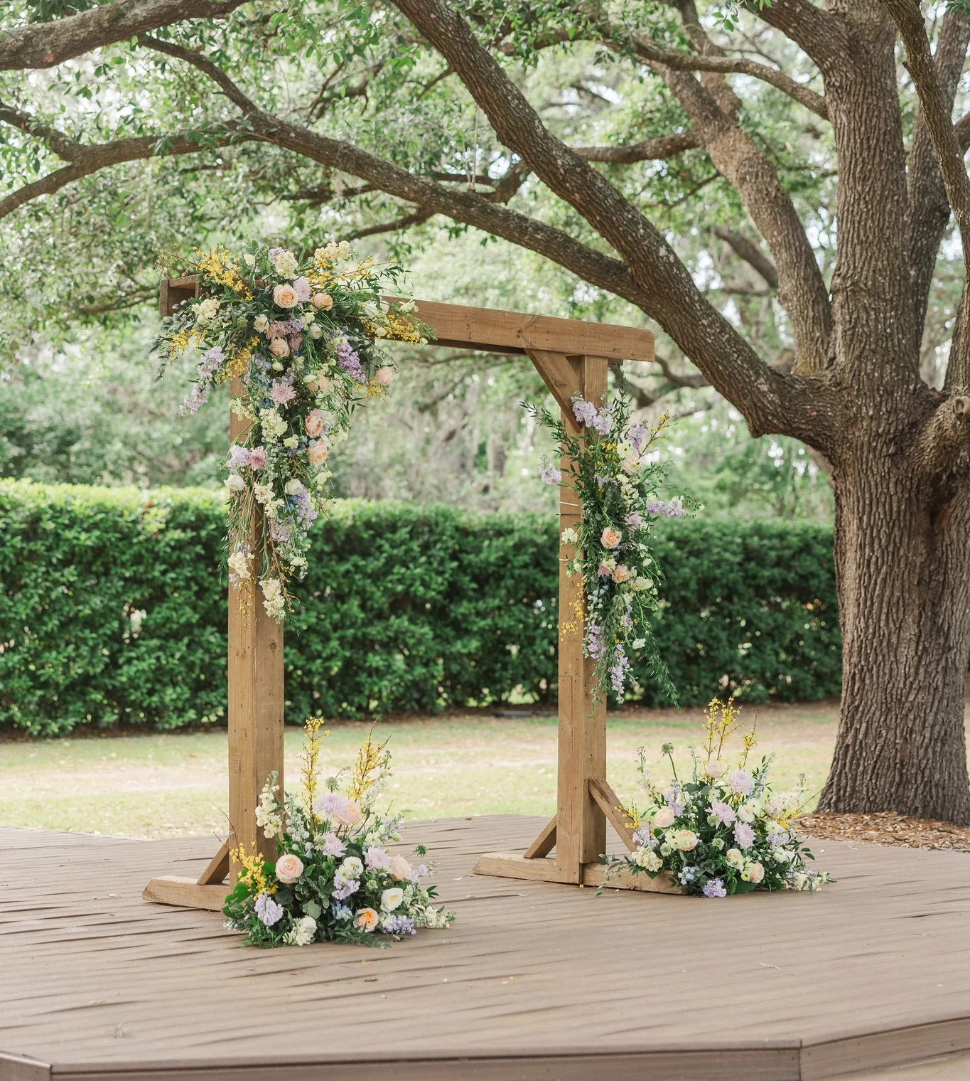 Wooden wedding arch adorned with flowers under a large tree