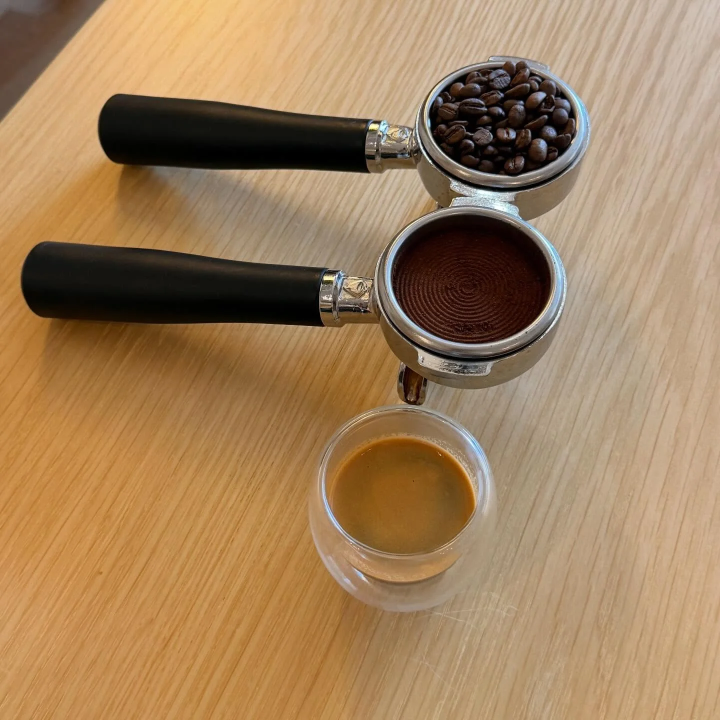 Espresso shot with coffee beans and portafilter on wooden table