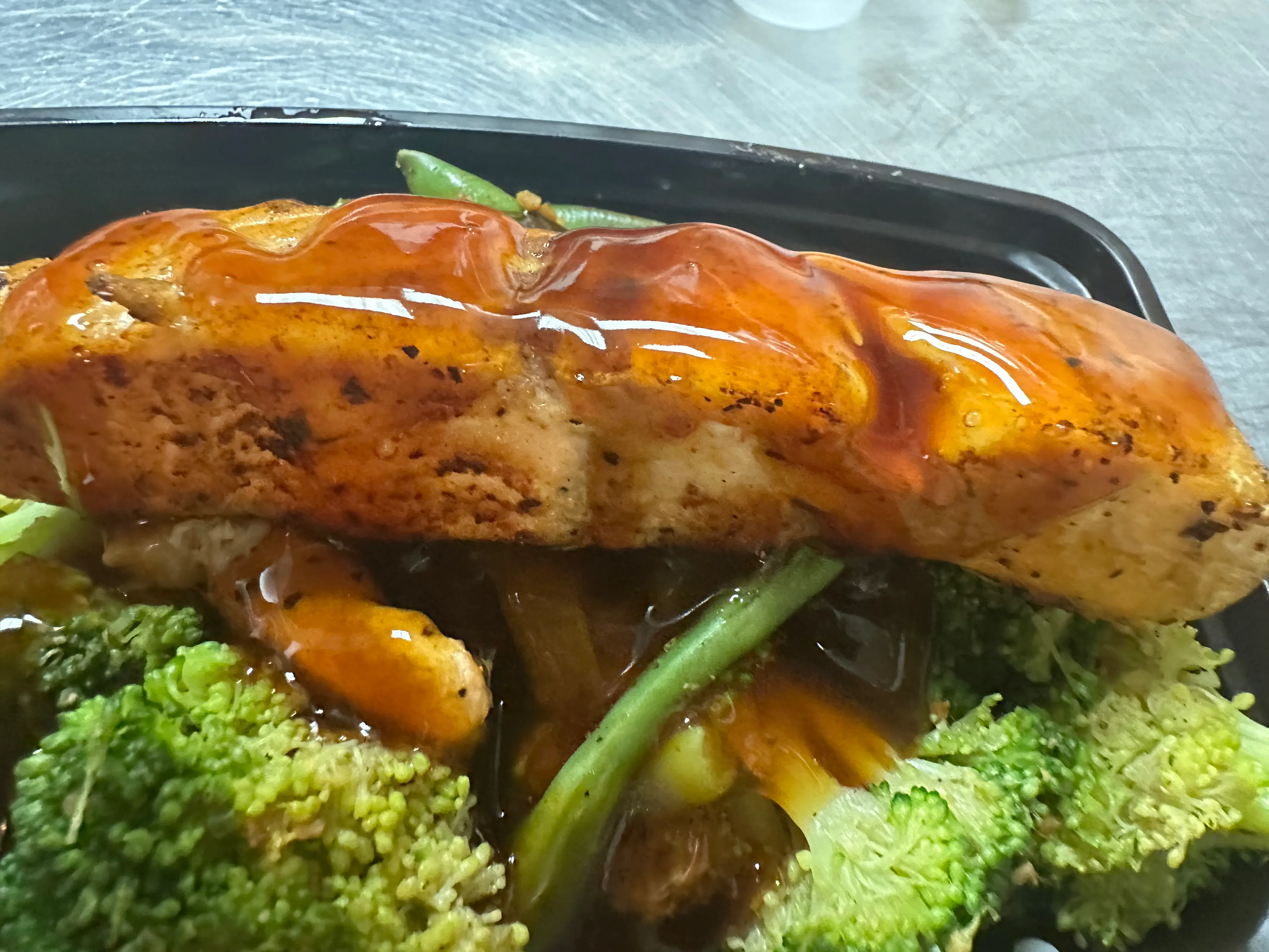Grilled teriyaki salmon with vegetables in a takeout container