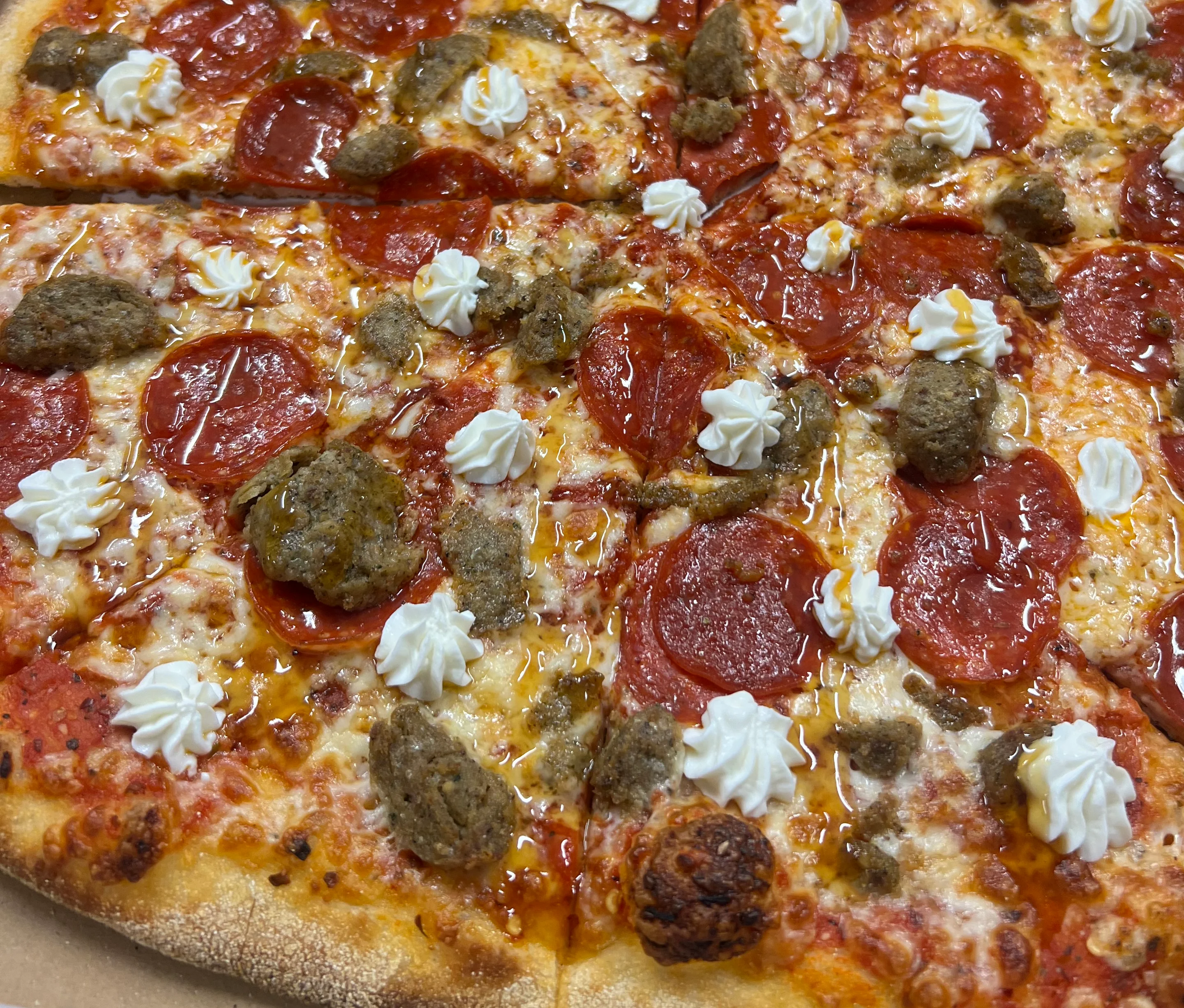 A baked pepperoni pizza with a slightly charred crust, served on a round metal tray with a pizza cutter nearby.