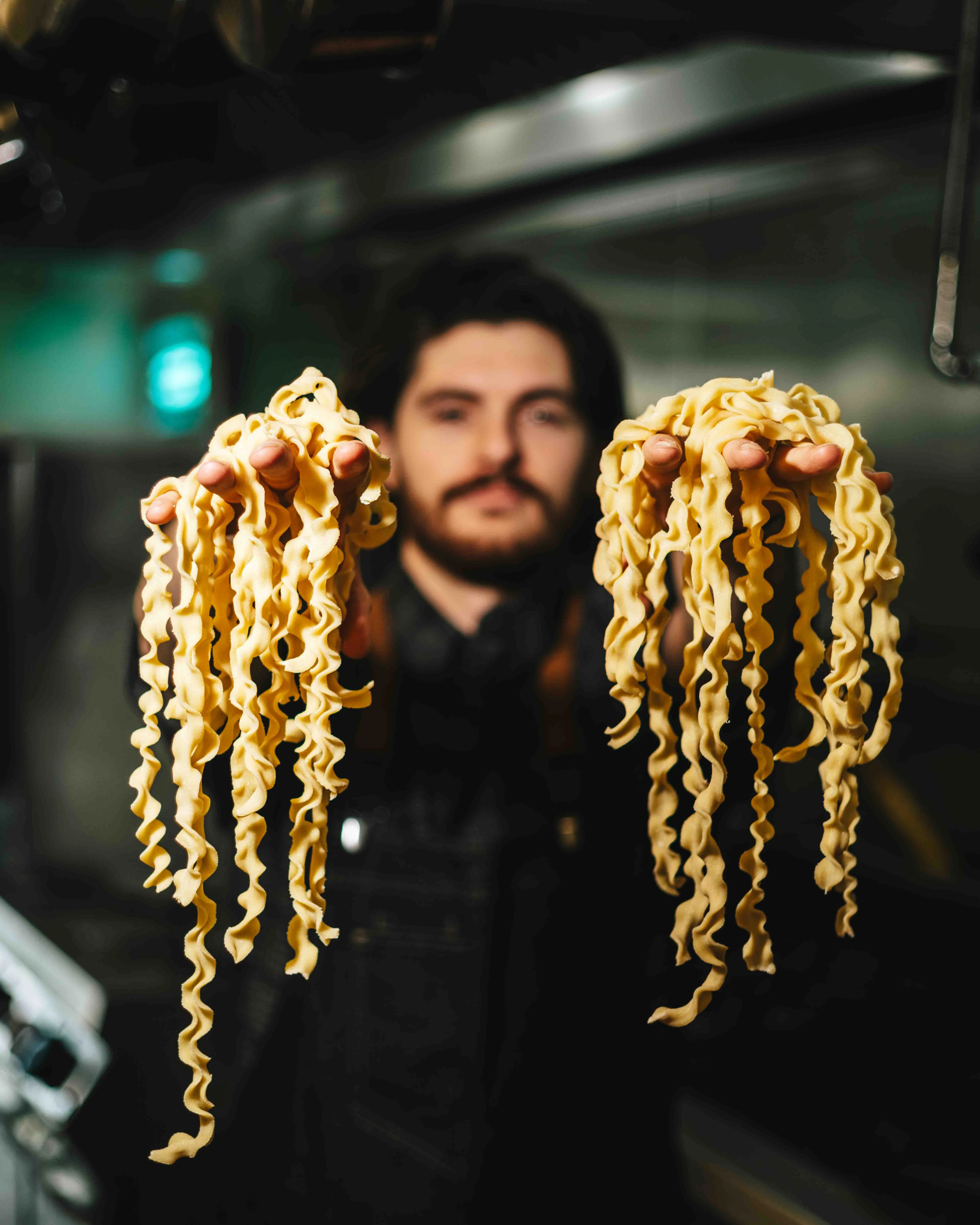 Freshly made Italian pasta strands in a chef's hands