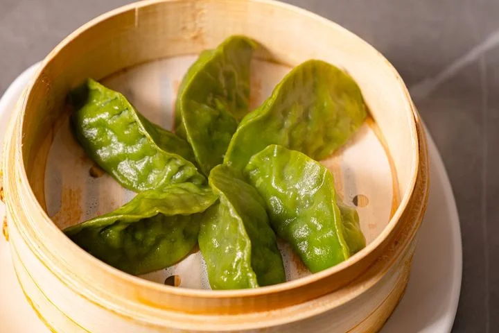 Steamed Chinese spinach dumplings in a bamboo basket