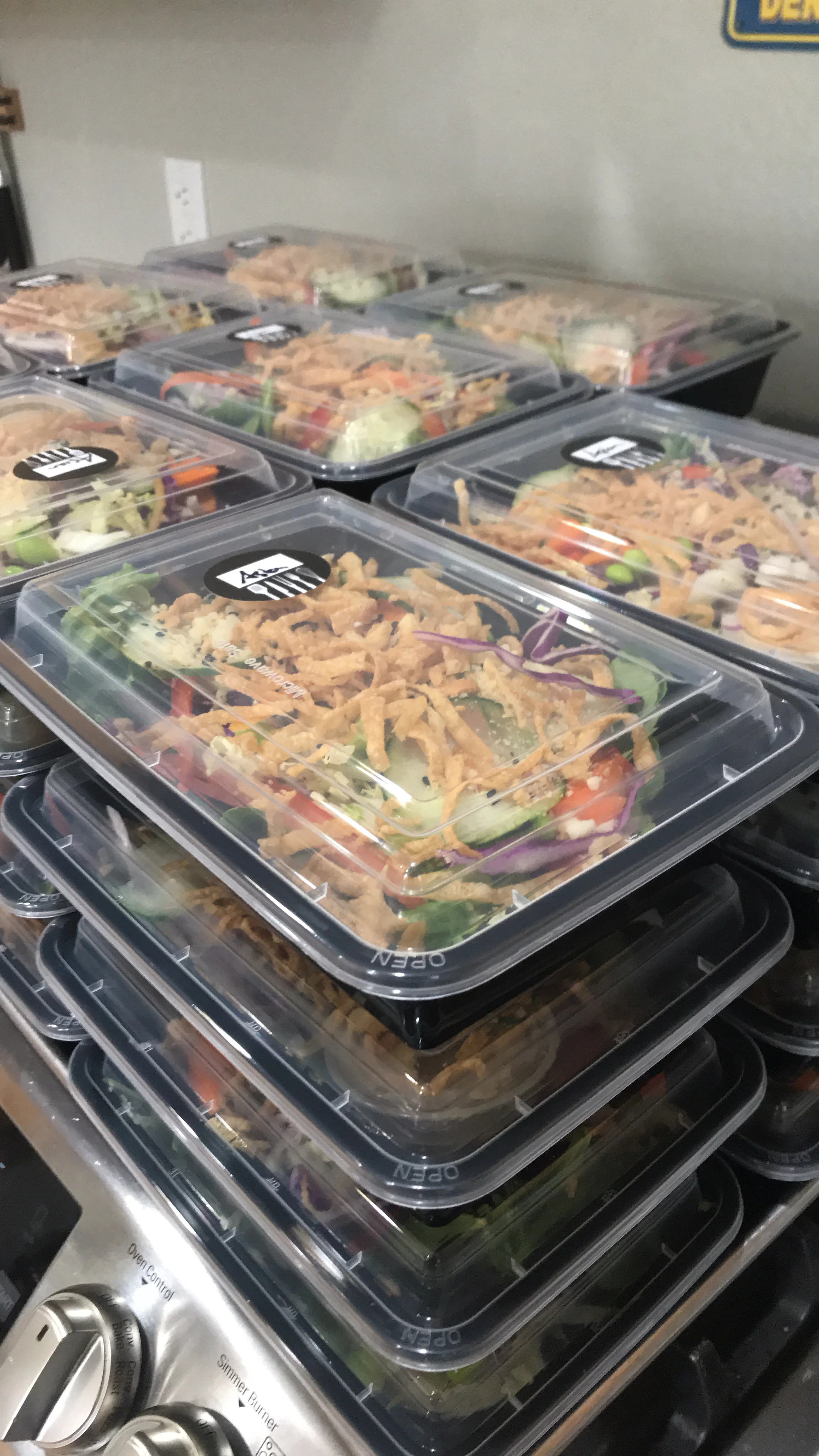 Freshly prepared Asian-style salad boxes stacked for service