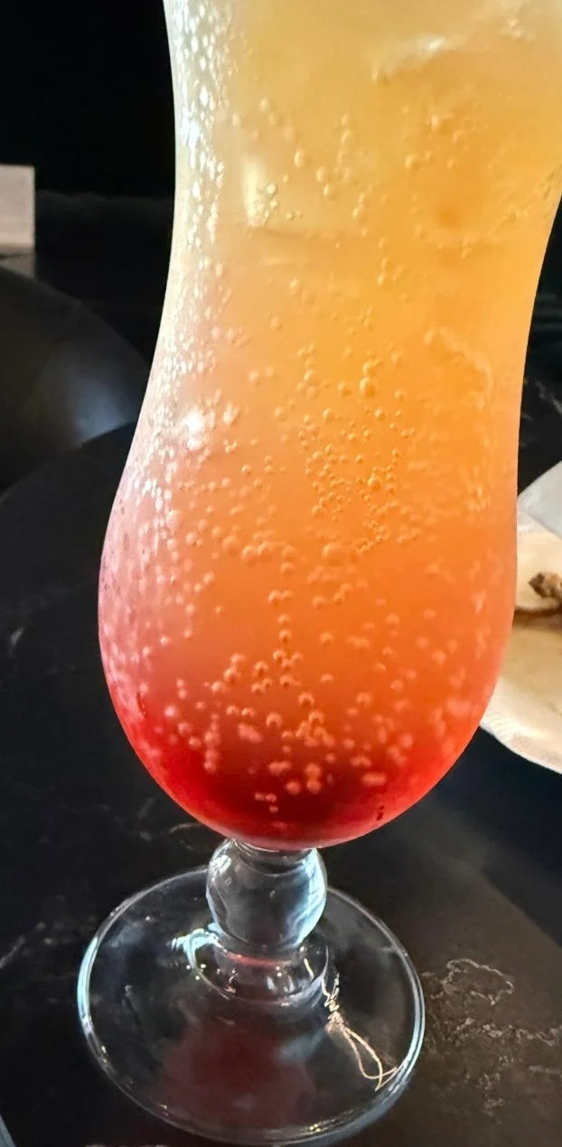 Colorful layered cocktail in a tall glass with bubbles