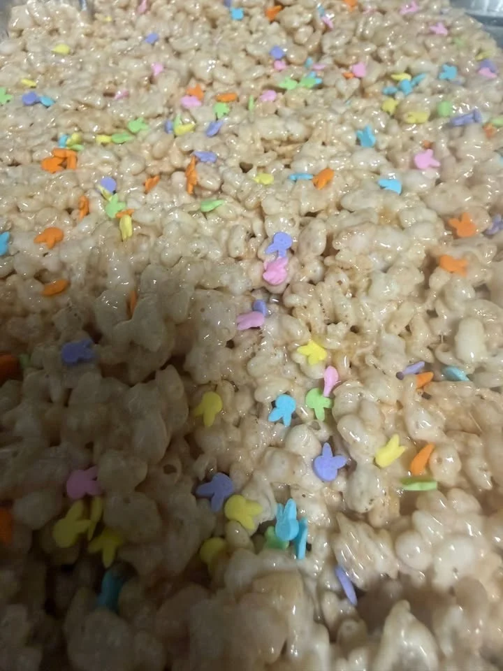 A close-up view of a mixture of puffed rice cereal coated in a sticky substance, garnished with colorful sprinkles.