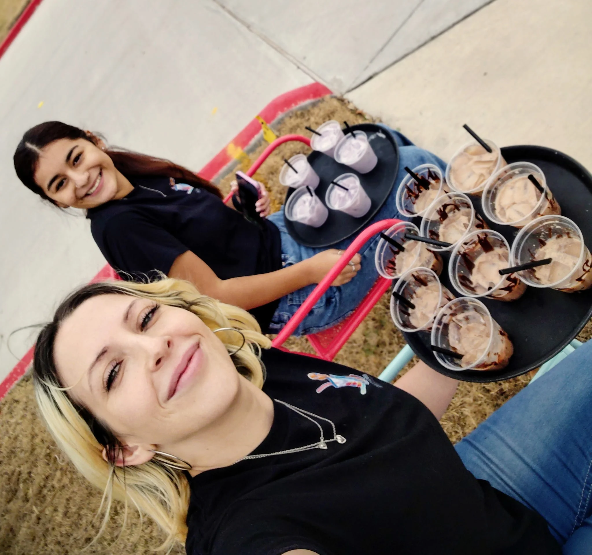 Two servers with trays of chocolate drinks outdoors