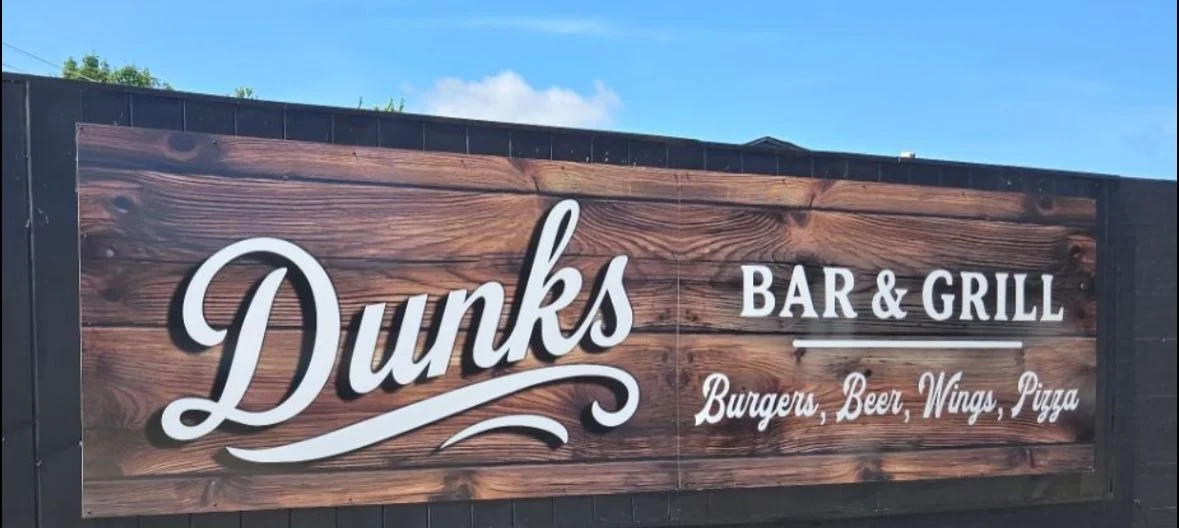 A large wooden wall sign reading “Dunks.”