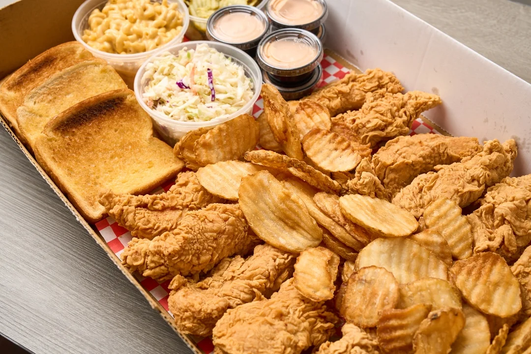A large platter featuring crispy fried chicken, golden toast, waffle fries, macaroni and cheese, and coleslaw.