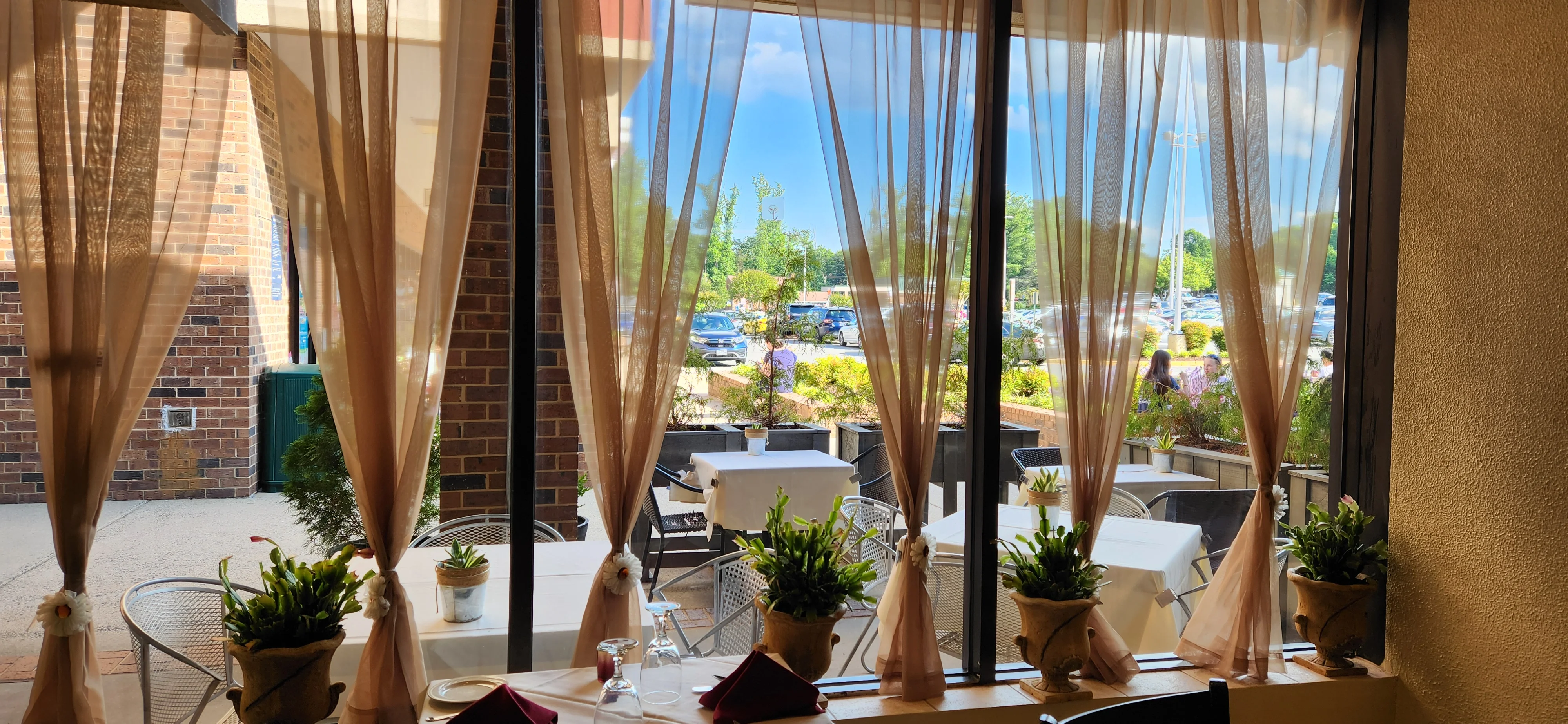 Cozy restaurant interior with sheer curtains and outdoor seating