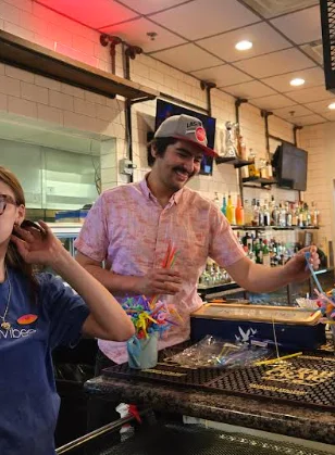 Bartender preparing colorful cocktails at a lively bar