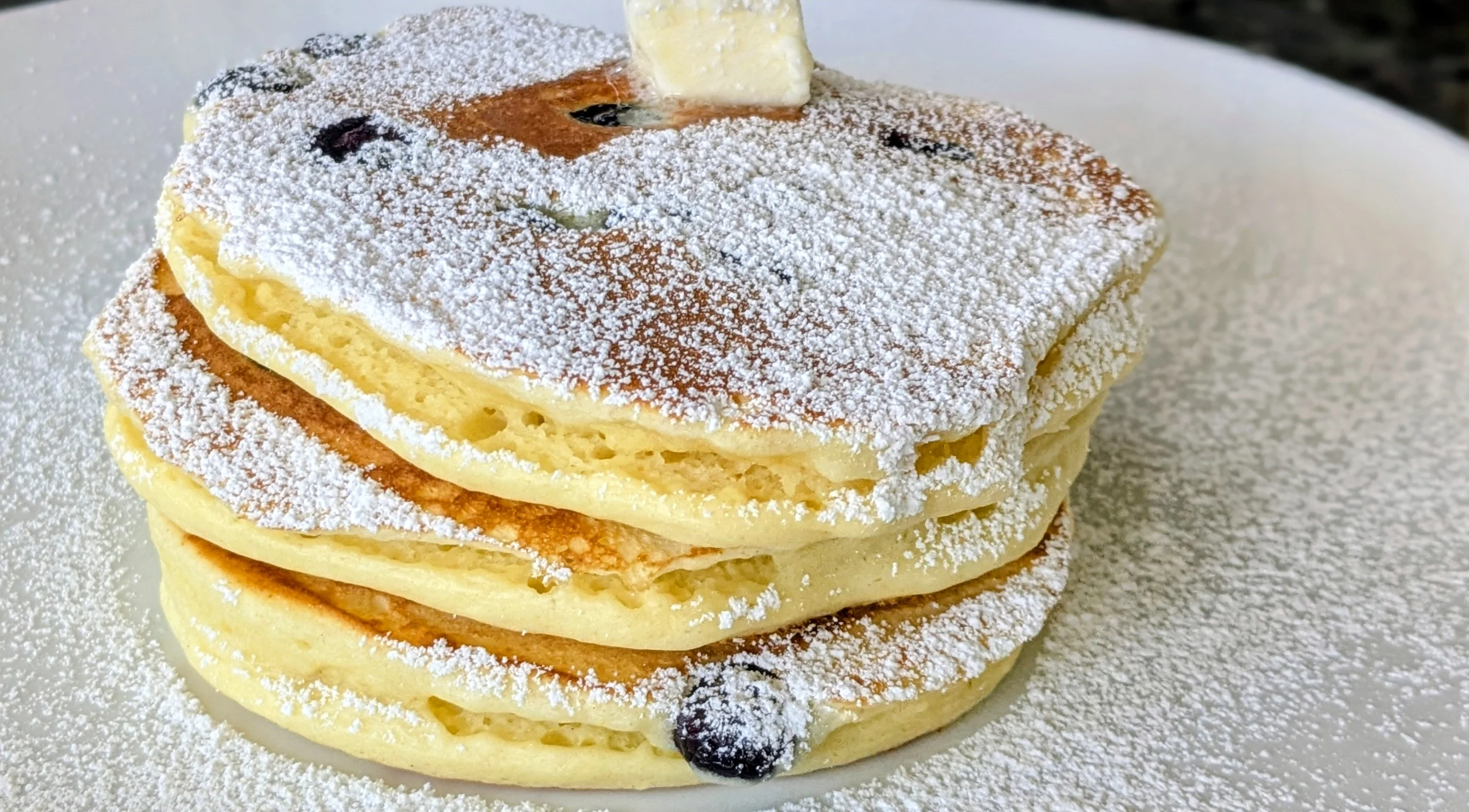 Fluffy blueberry pancakes dusted with powdered sugar