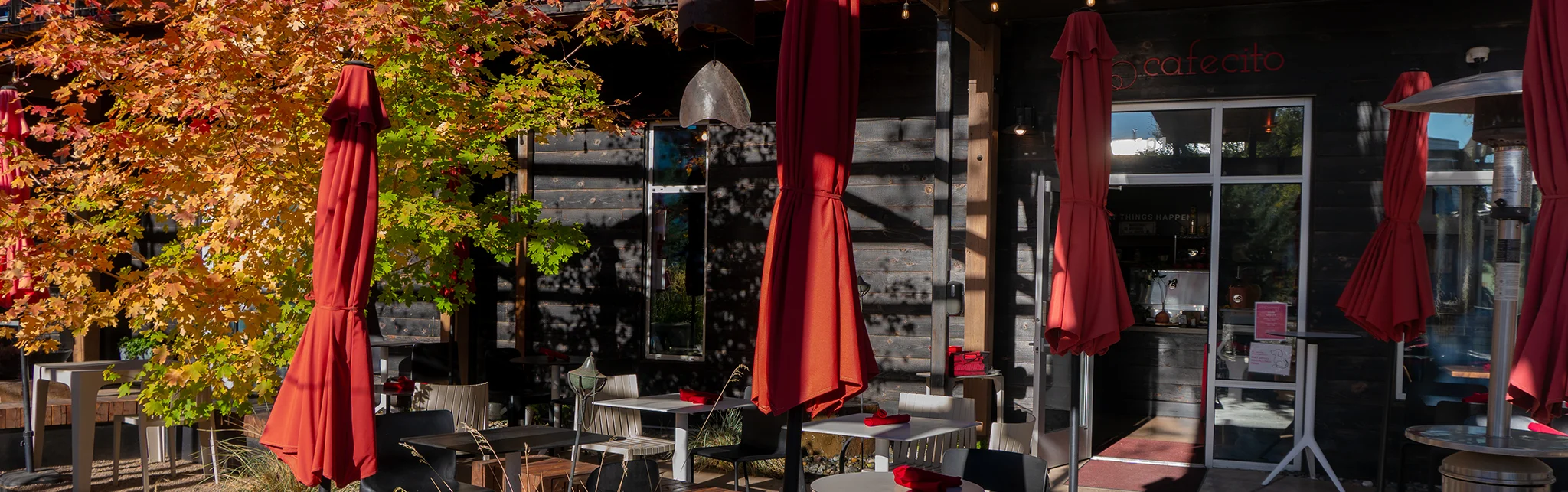 Charming restaurant patio with autumn foliage and red umbrellas