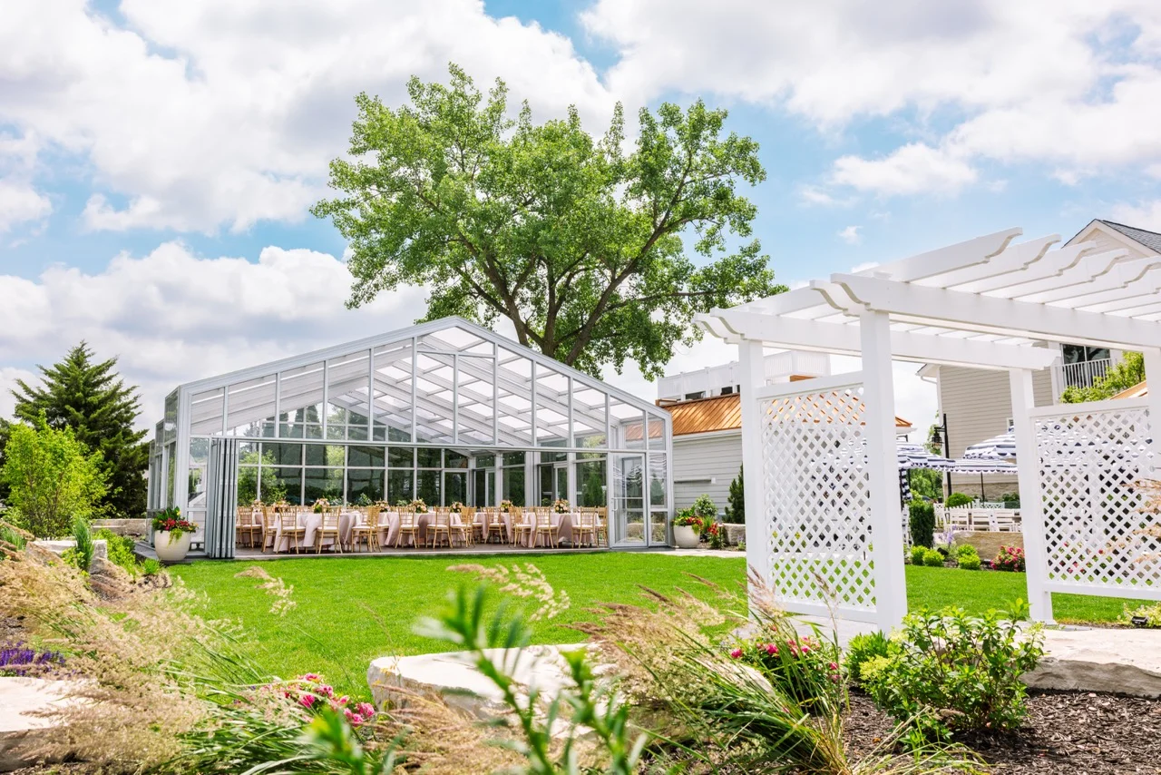 A glass atrium with tables, pink linens and a beautiful sky as the backdrop