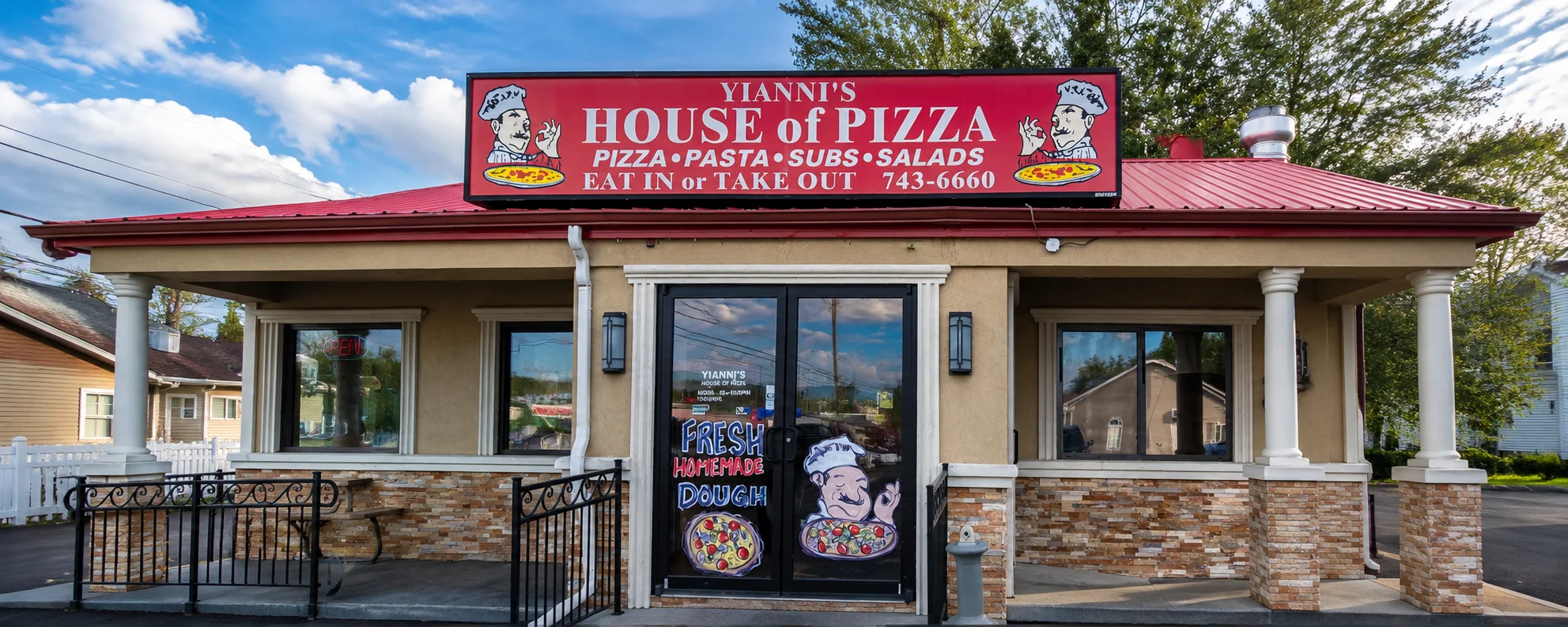 Exterior view of a pizza restaurant with a red roof and parking area.