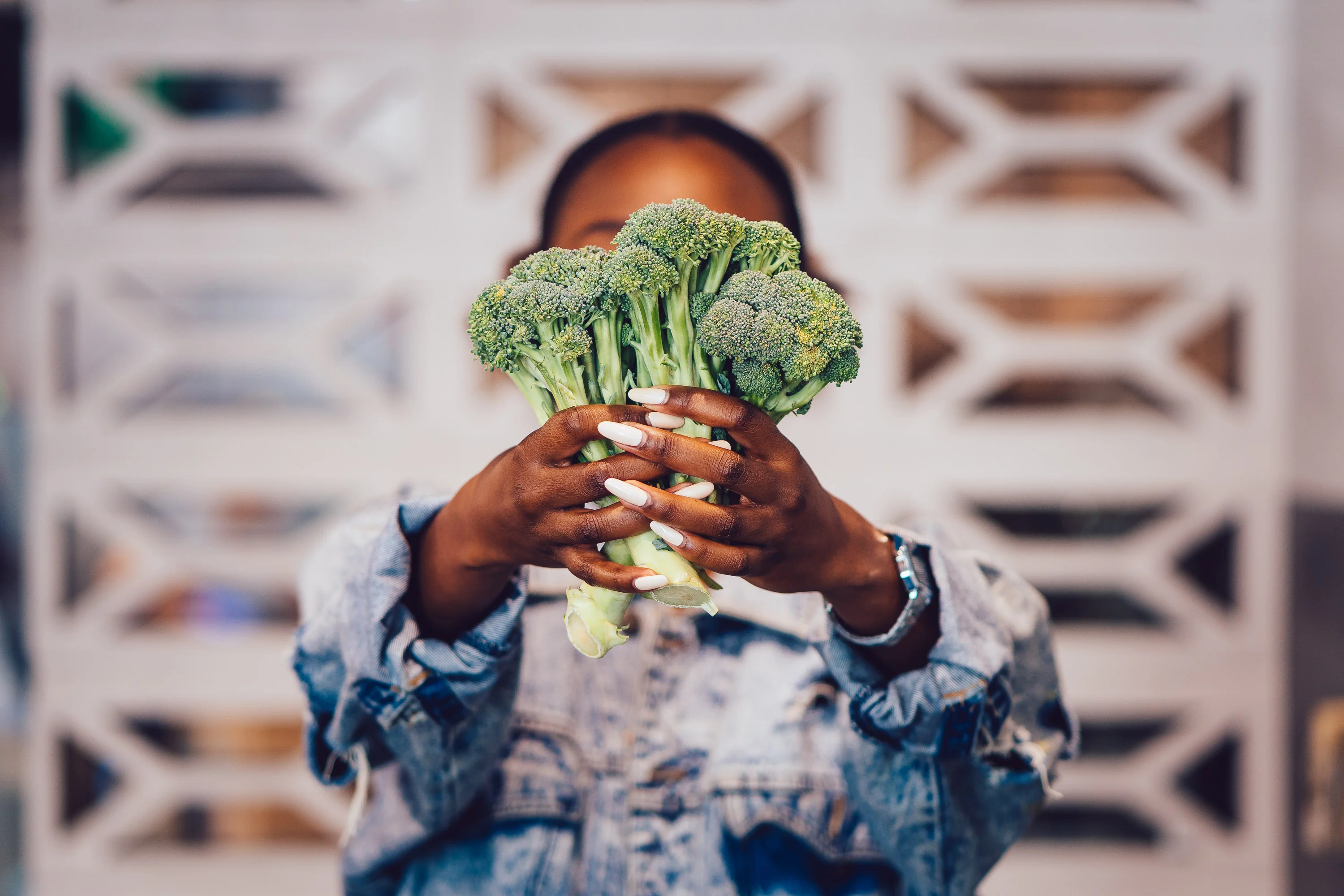 Fresh broccoli held by hands in a modern kitchen setting